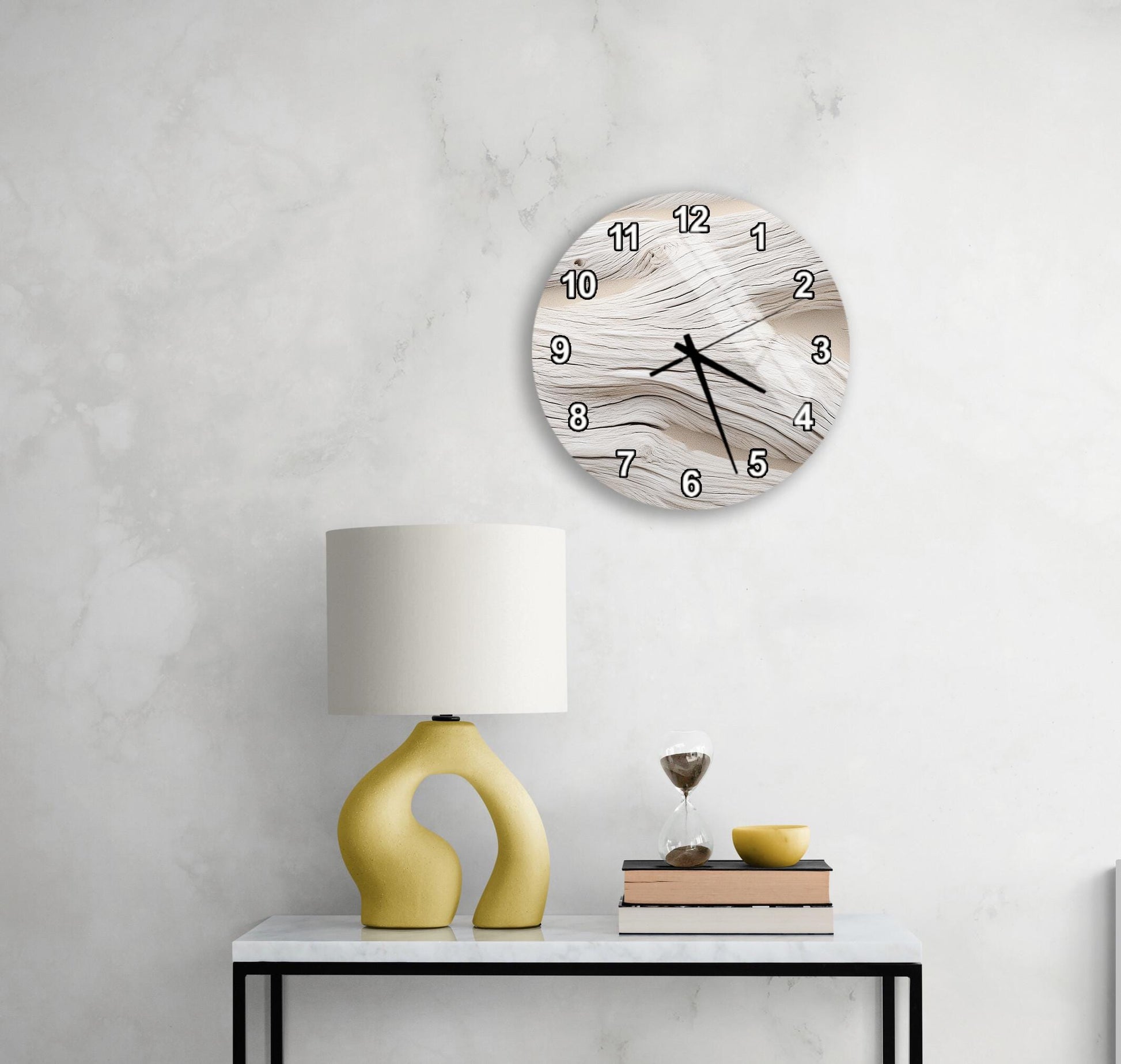 a modern living room with a white marble wall, a round clock with a unique design, a yellow lamp with a curved base, a stack of books, and a glass of wine on a white table.