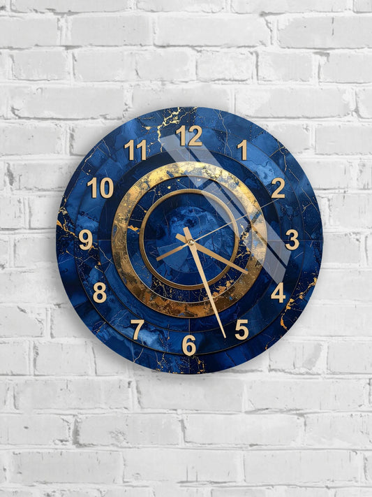 A blue and gold wall clock with a marble-like texture and gold hands is mounted on a white brick wall.