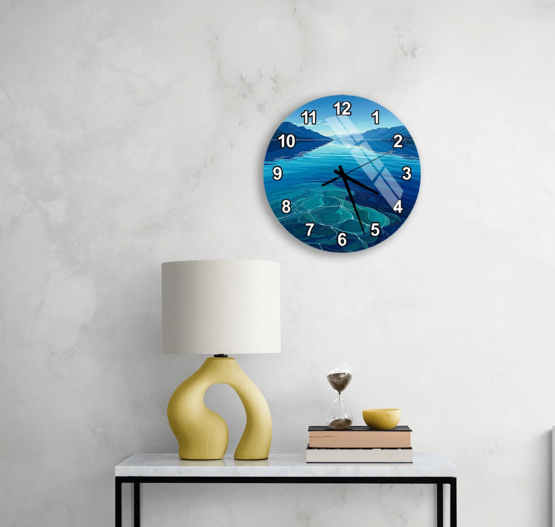 a wall clock with a blue ocean scene, a yellow lamp on a white table, and a stack of books on the table.