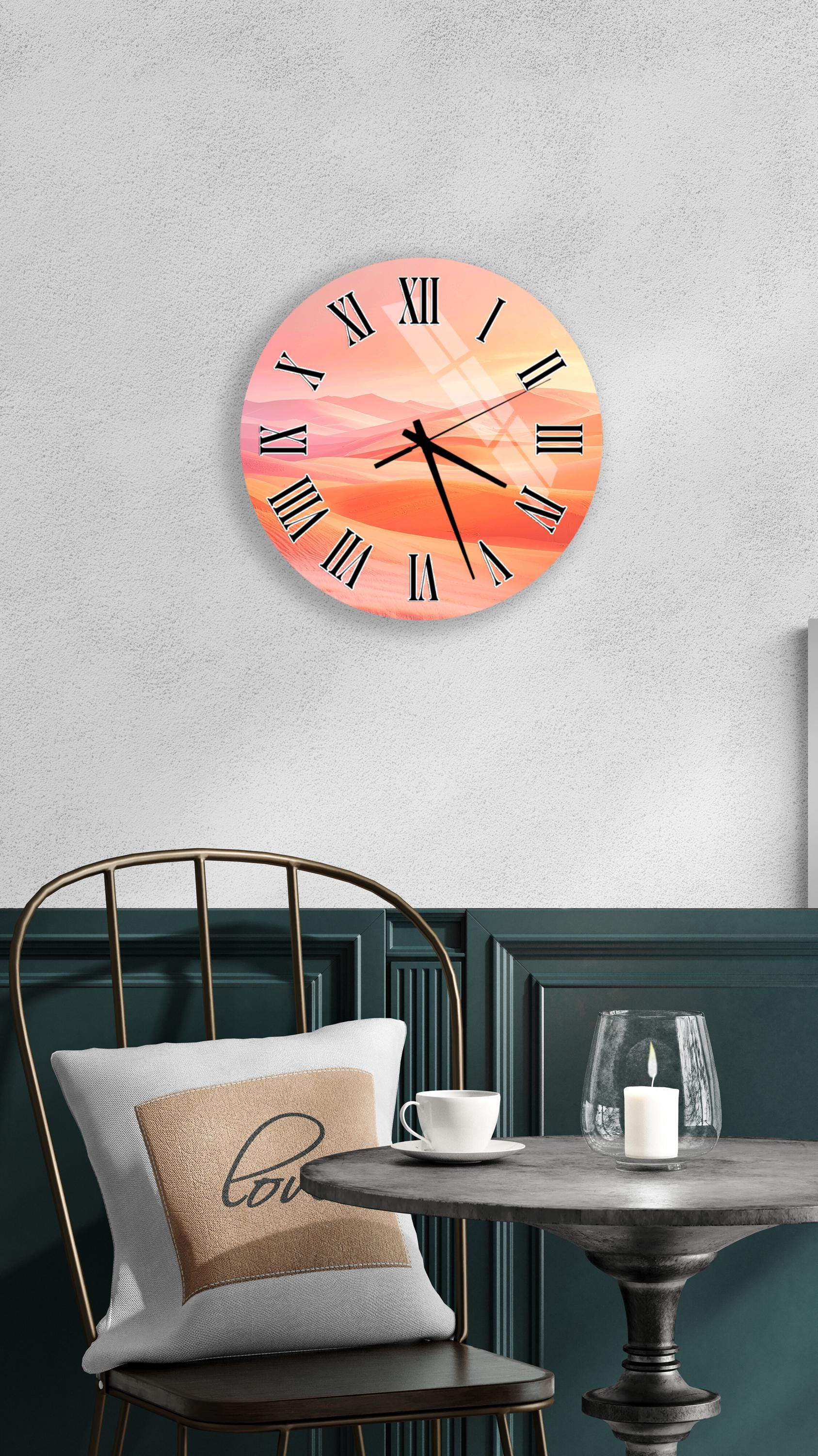 a wall clock with a sunset-like design, mounted on a wall above a table with a white tablecloth and a candle.