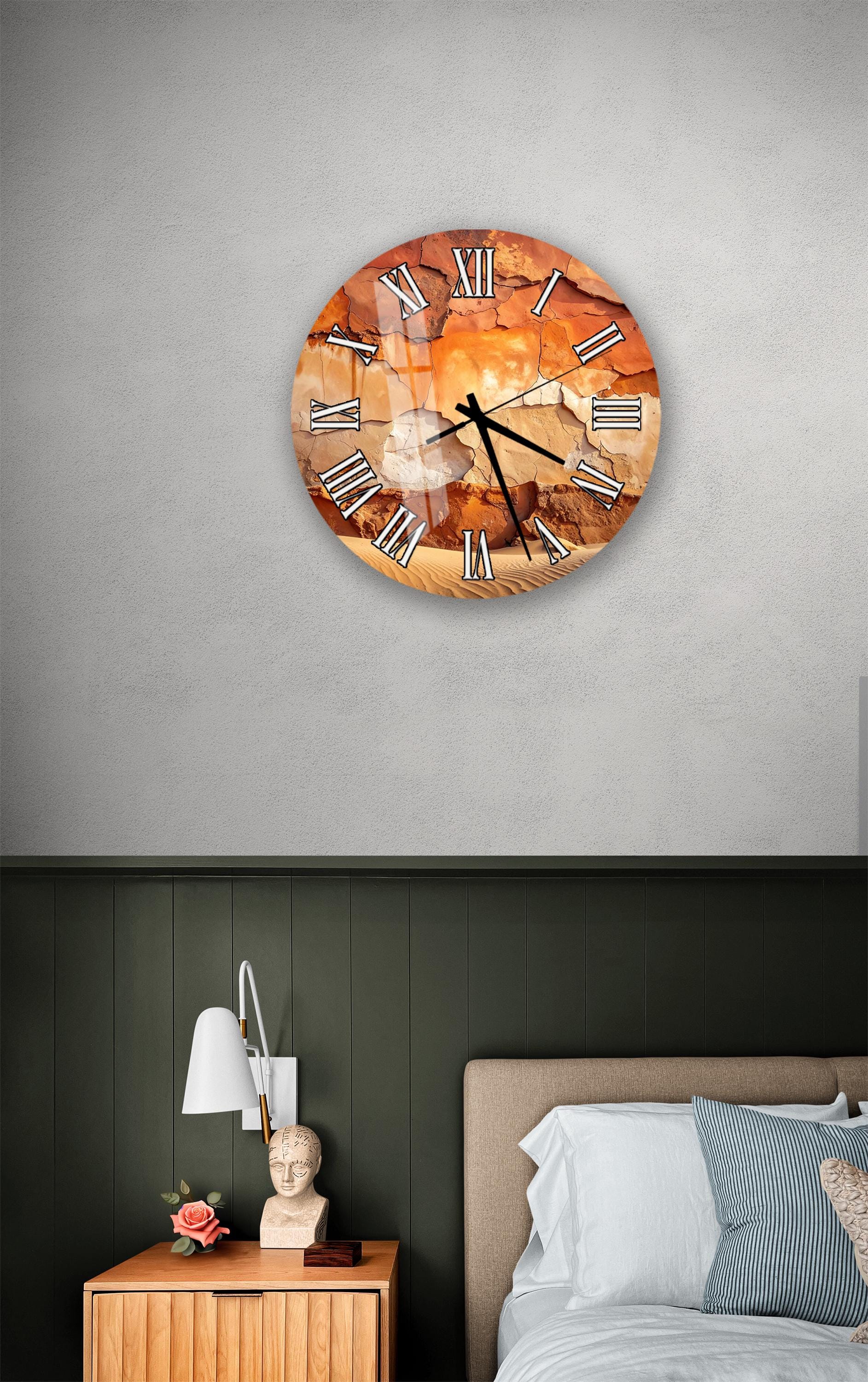 a bedroom setting with a large, round clock hanging on the wall above a bed. The clock has a unique, textured design and is positioned at eye level. The room also includes a nightstand with a lamp and a small statue or bust.