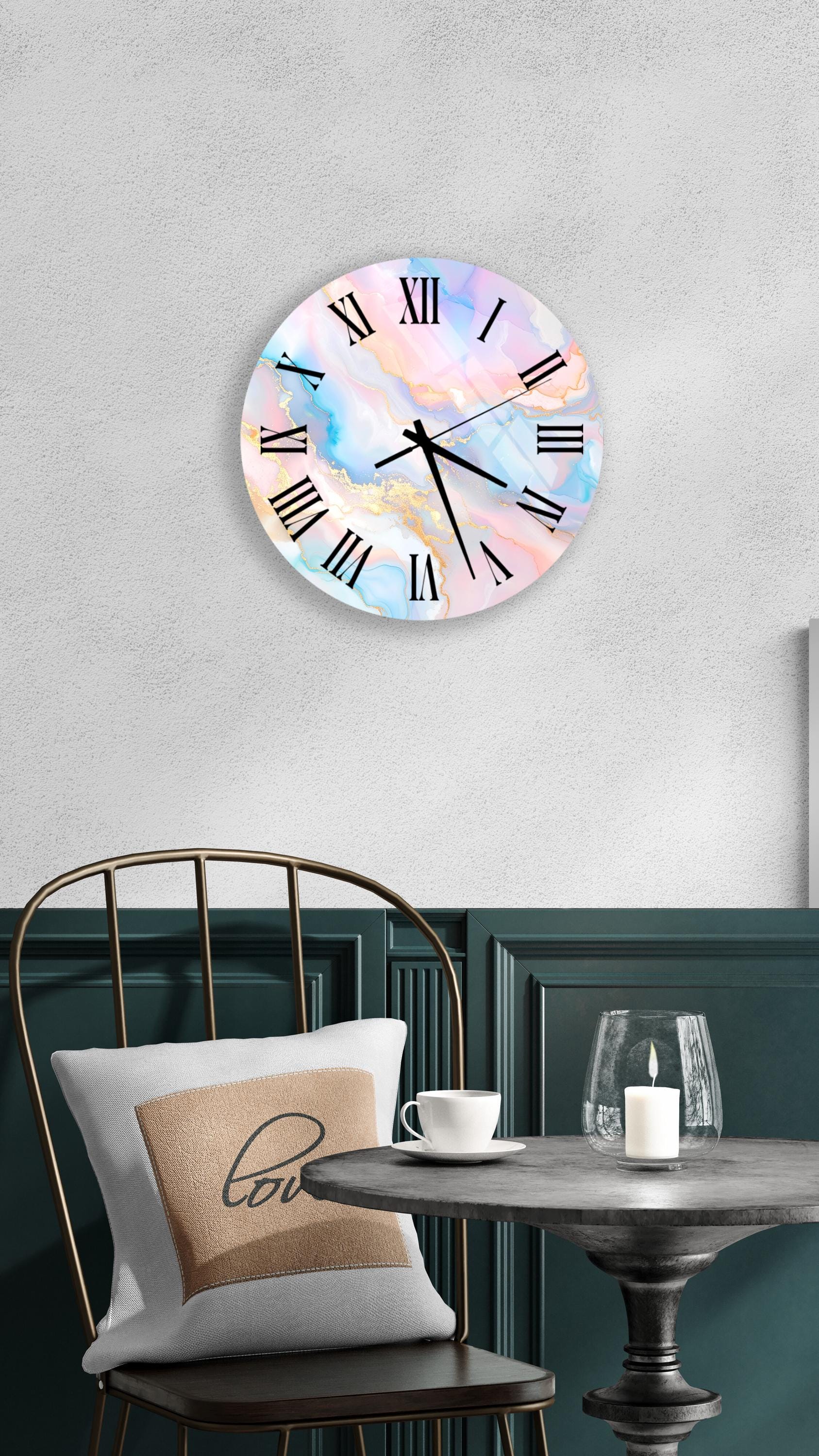 a wall clock with a pastel color palette, a round table with a white cup and a candle, and a chair with a pillow that says 'love'.