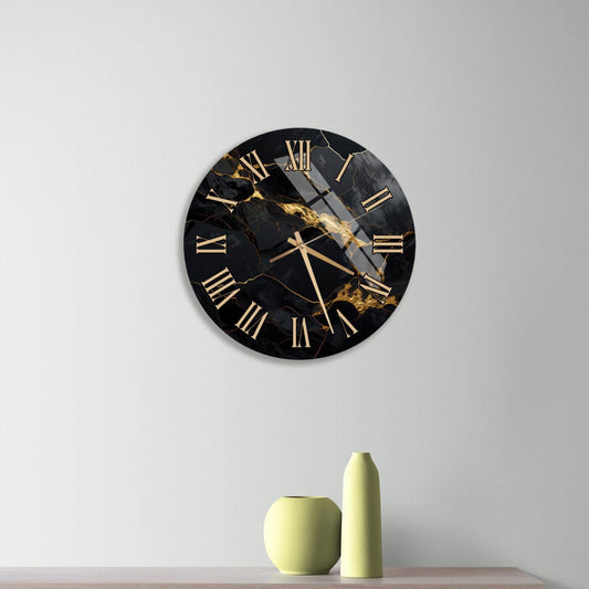 a modern black and gold clock with Roman numerals, mounted on a wall above a wooden dresser with three drawers.