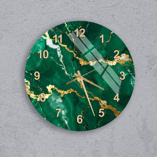 A wall clock with a green marble-like design and gold accents, mounted on a concrete wall.