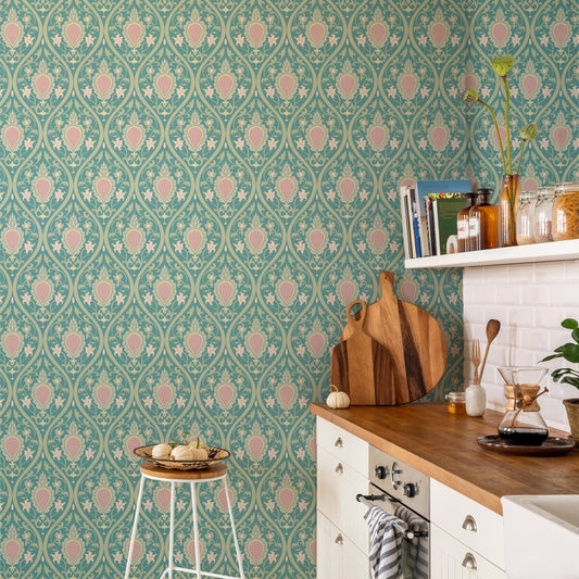 a kitchen with a wooden cutting board, a white stool, and various kitchen items such as a vase, a book, and a pitcher. The kitchen has a patterned wallpaper and a white countertop.