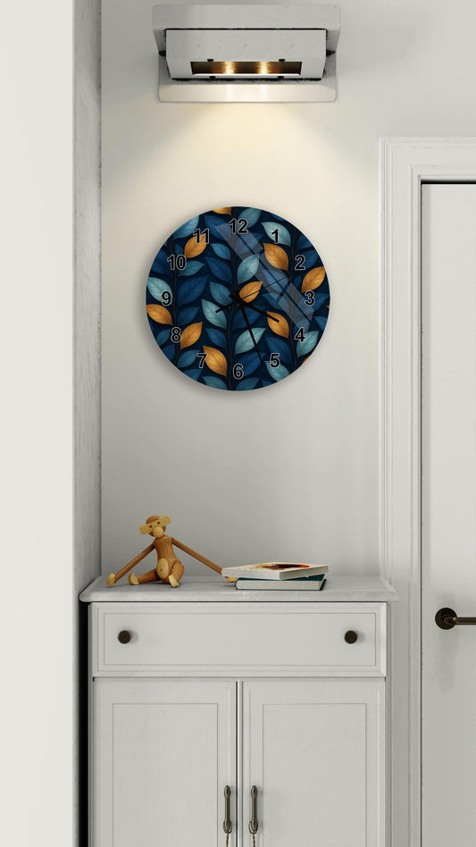 a wall clock with a leafy blue and orange design, mounted on a white wall above a white cabinet.