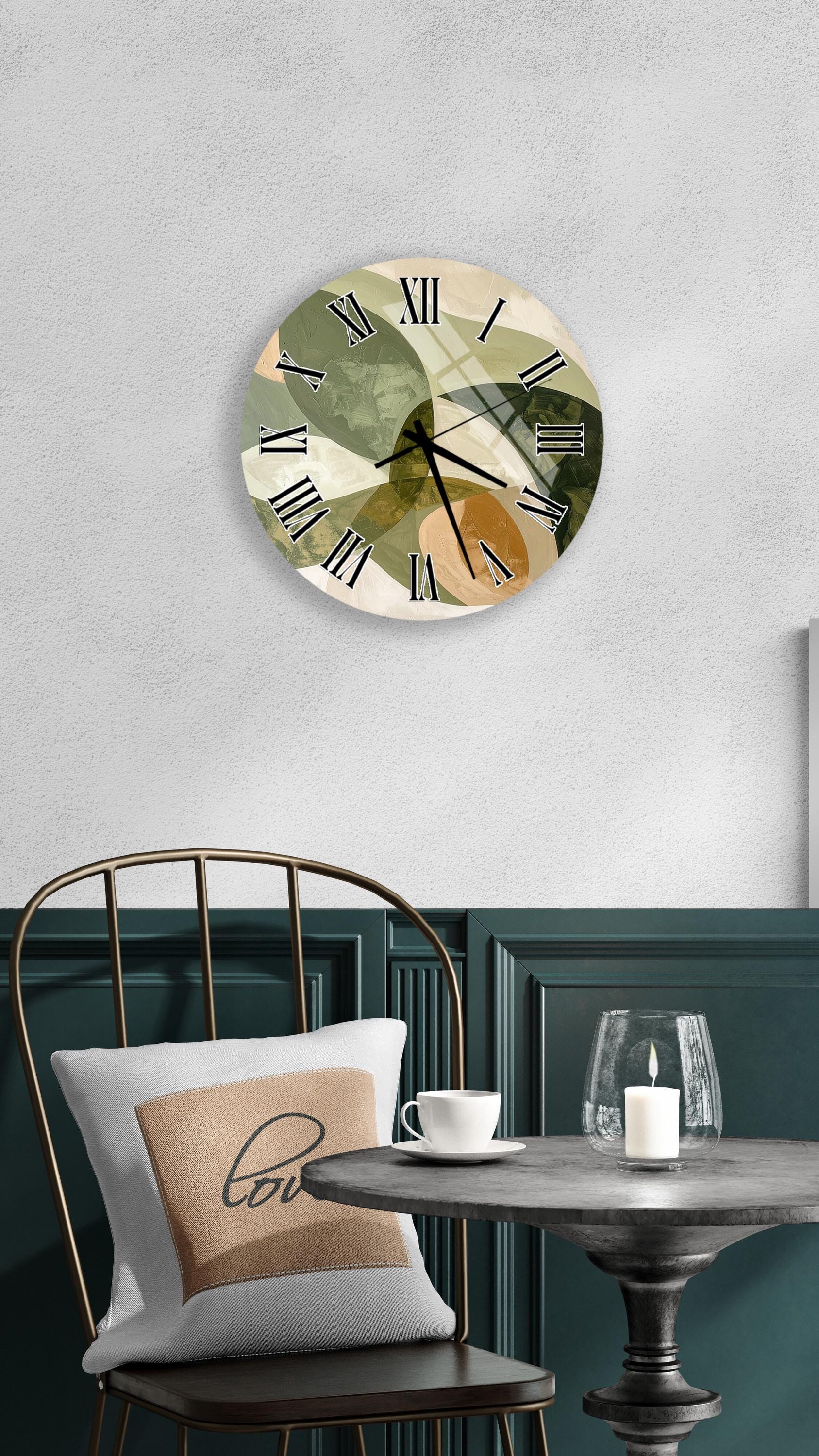a wall clock with a unique abstract design, a white table with a candle and a cup, and a green chair with a pillow.