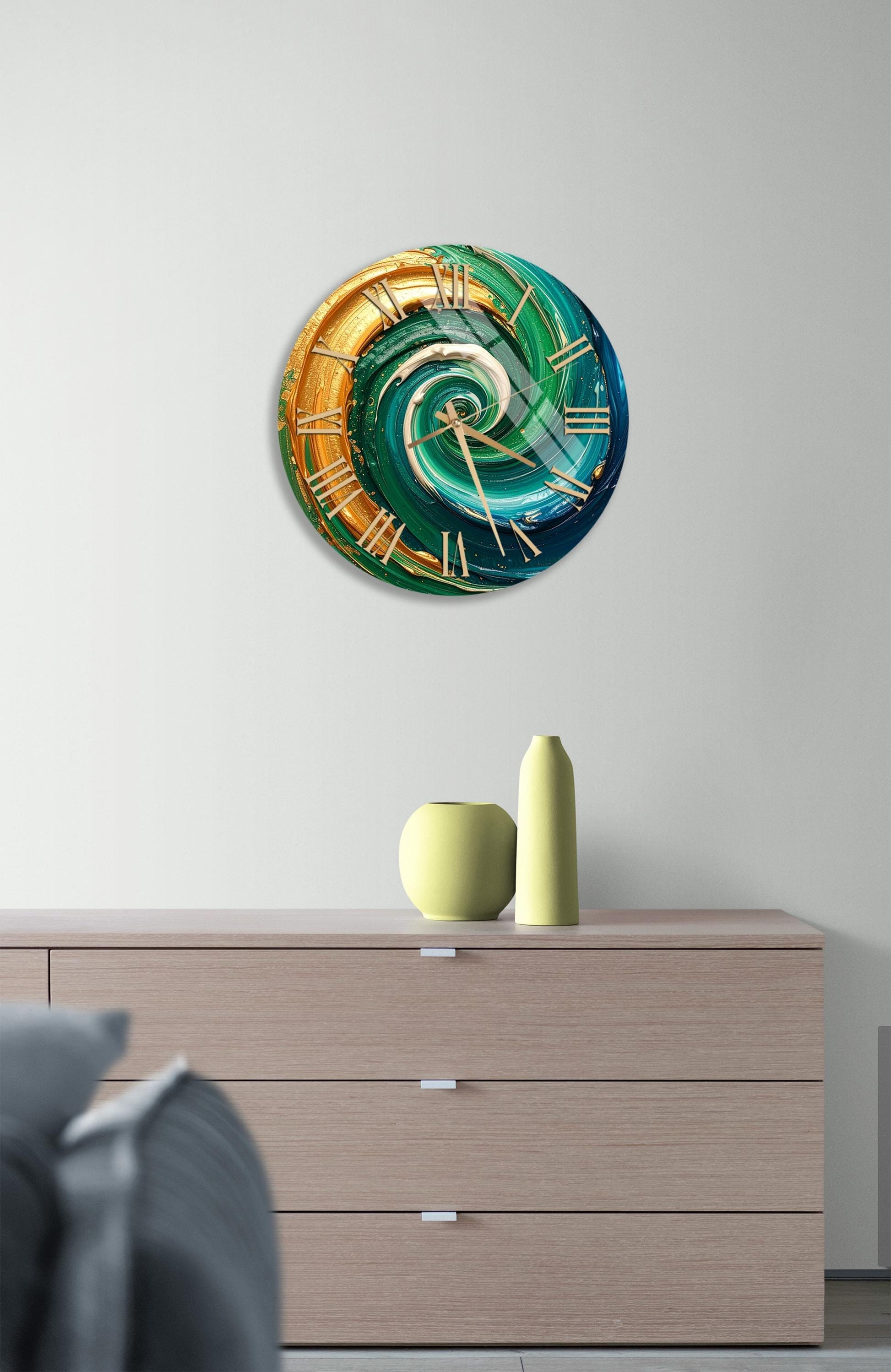 a modern clock with a spiral design in shades of green, blue, and orange, mounted on a wall above a wooden dresser.