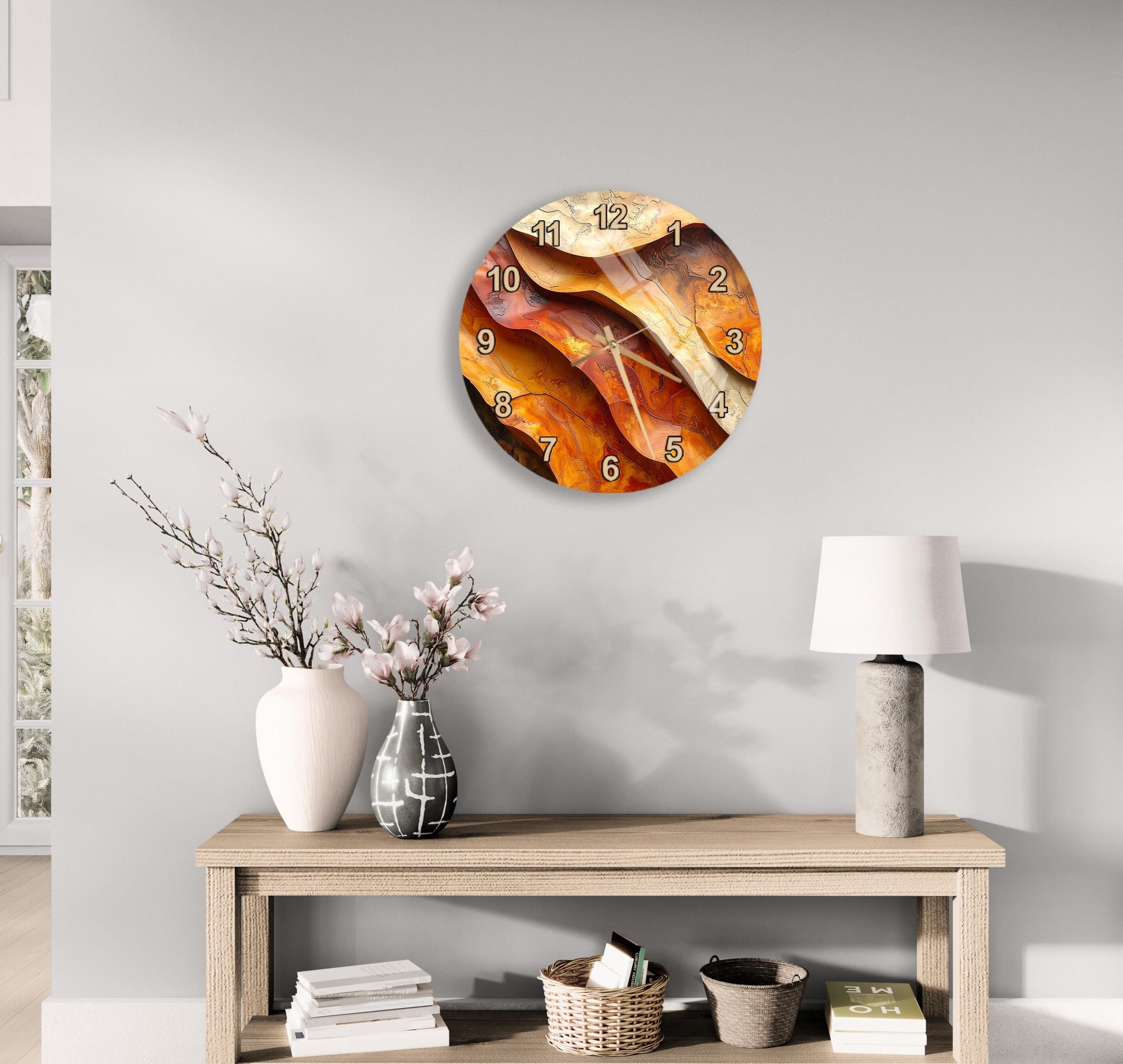 a modern wall clock with a unique, abstract design, hanging above a wooden table with a lamp and decorative items such as a vase with flowers and a stack of books.