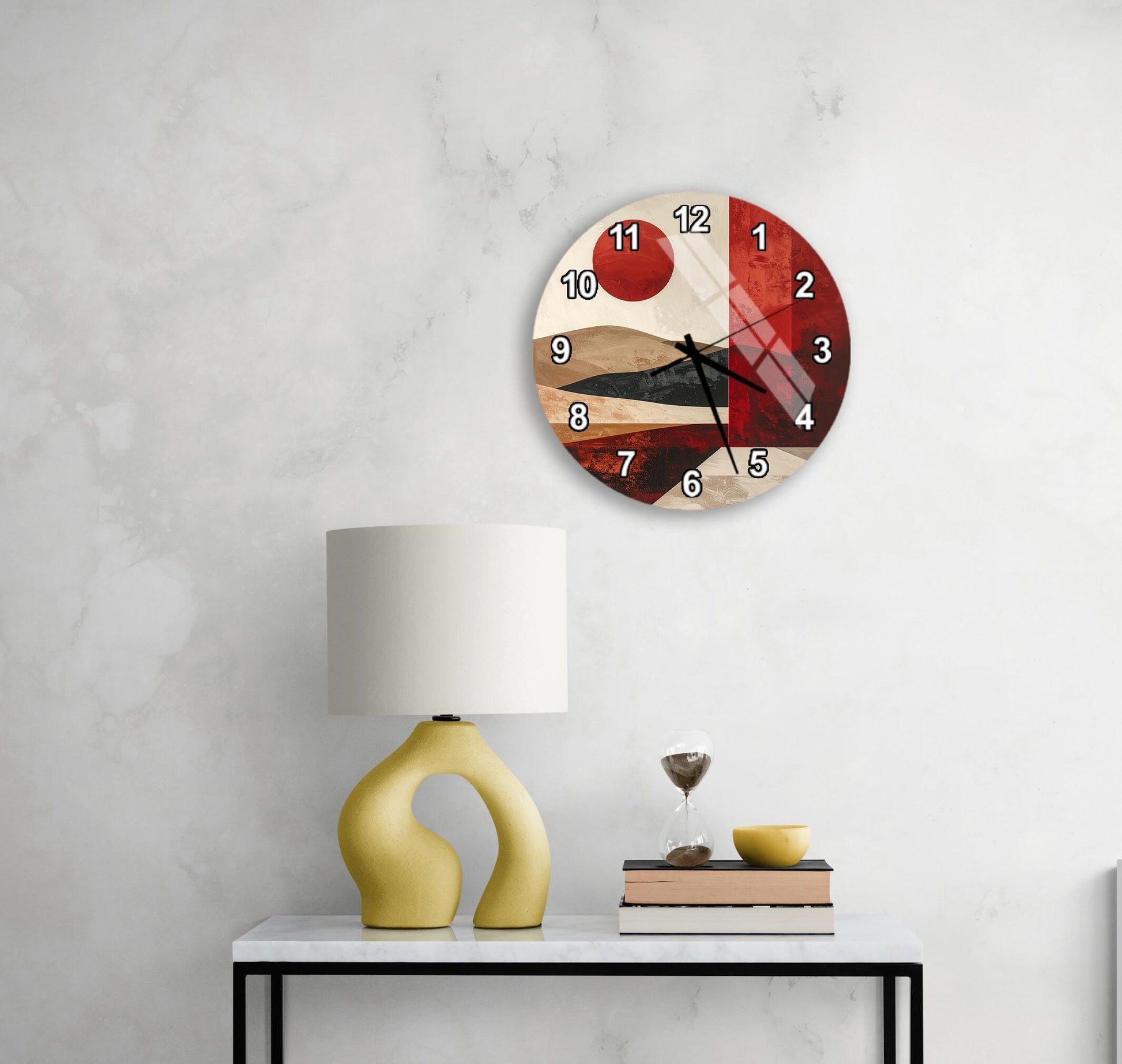 a modern wall clock with a unique design, a yellow table lamp, a stack of books, and a glass of wine on a white table.