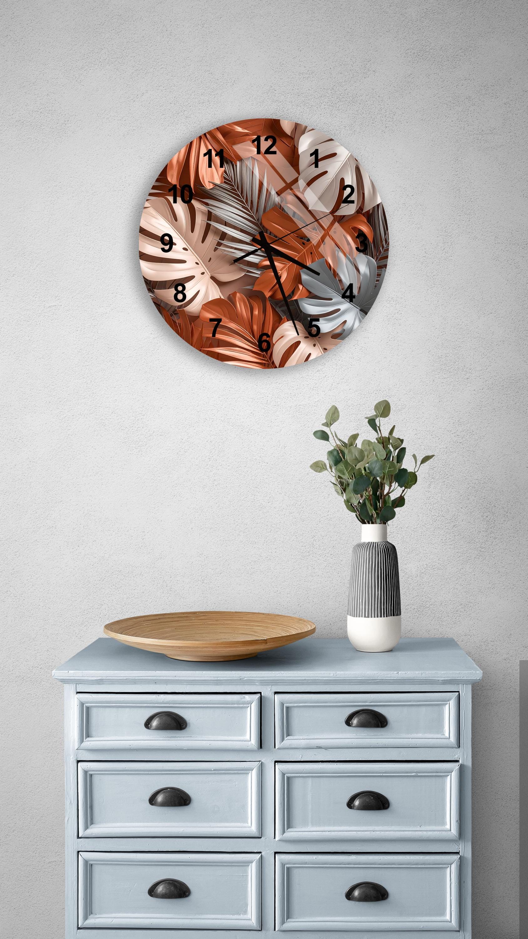 a wall clock with a tropical leaf pattern, a wooden tray, a vase with greenery, and a gray dresser with six drawers.