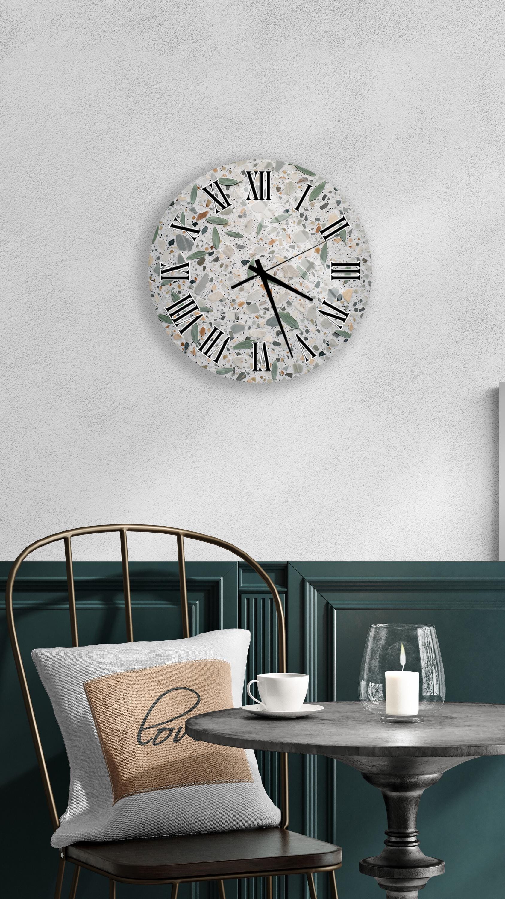 a modern and stylish interior design with a round wall clock, a white table with a candle, and a black chair with a pillow.