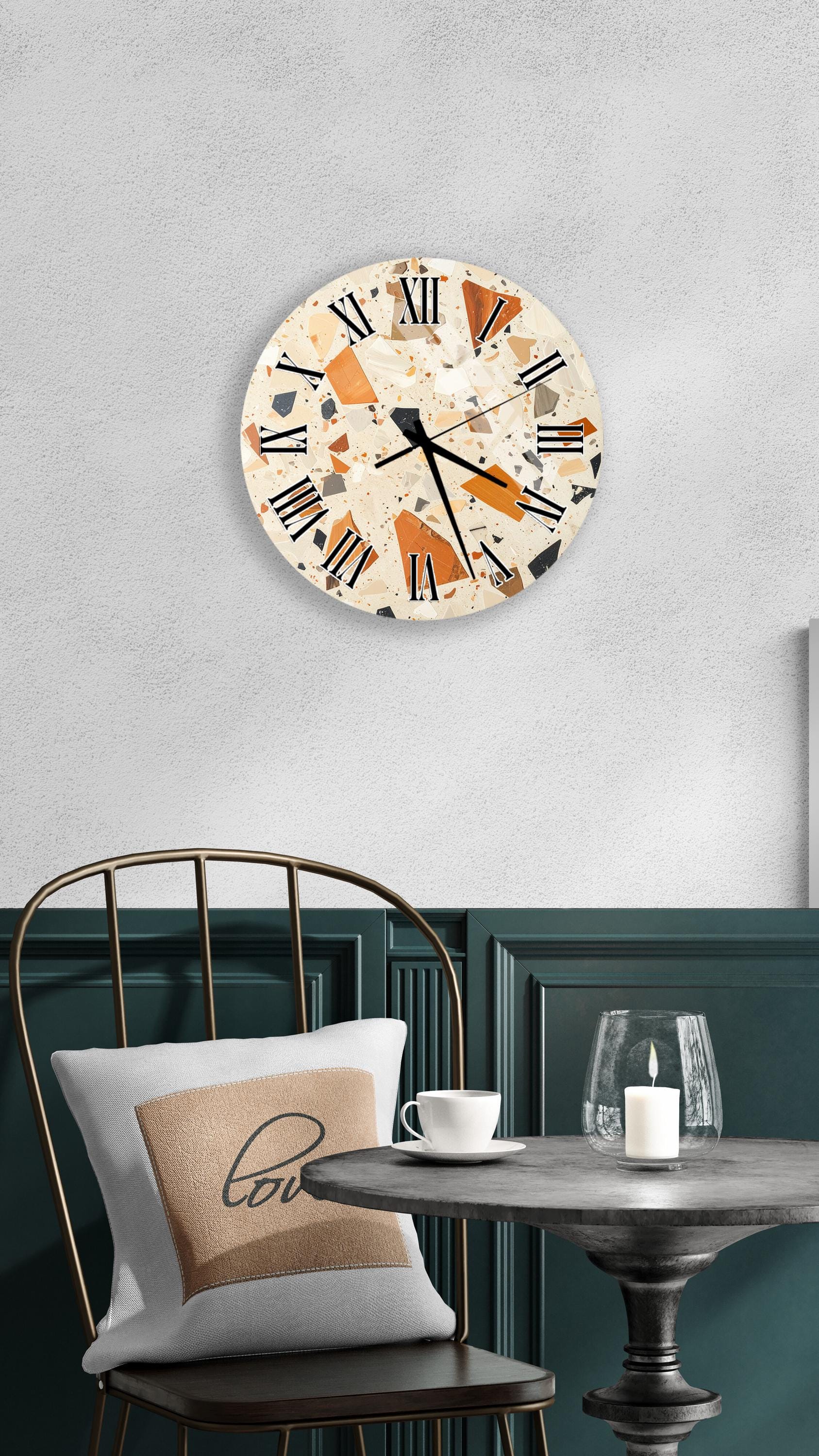 a modern interior design with a round wall clock displaying Roman numerals, a white table with a candle and a cup, and a black chair with a pillow.