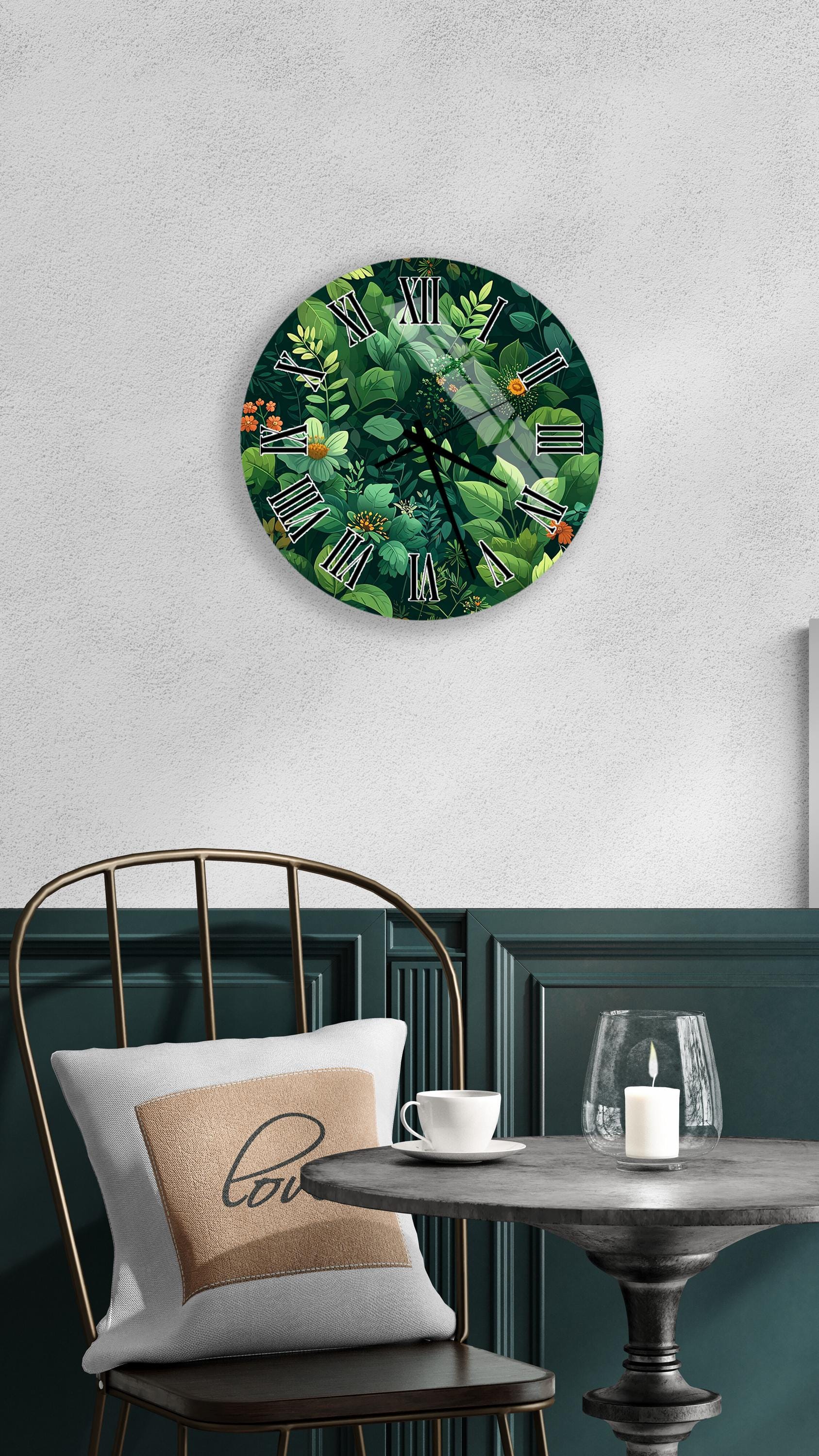 a round wall clock with a green and leafy design, mounted on a white wall above a table with a white tablecloth. The table has a white cup and a candle on it, creating a cozy and inviting atmosphere.
