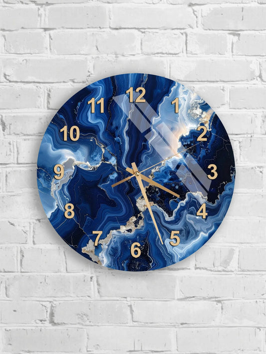 A round wall clock with a marble-like blue and white swirl pattern, mounted on a white brick wall.