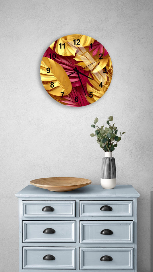 a wall clock with a vibrant design of yellow and red leaves, mounted on a wall above a light blue dresser with six drawers. The dresser also has a vase with greenery and a wooden tray on top.