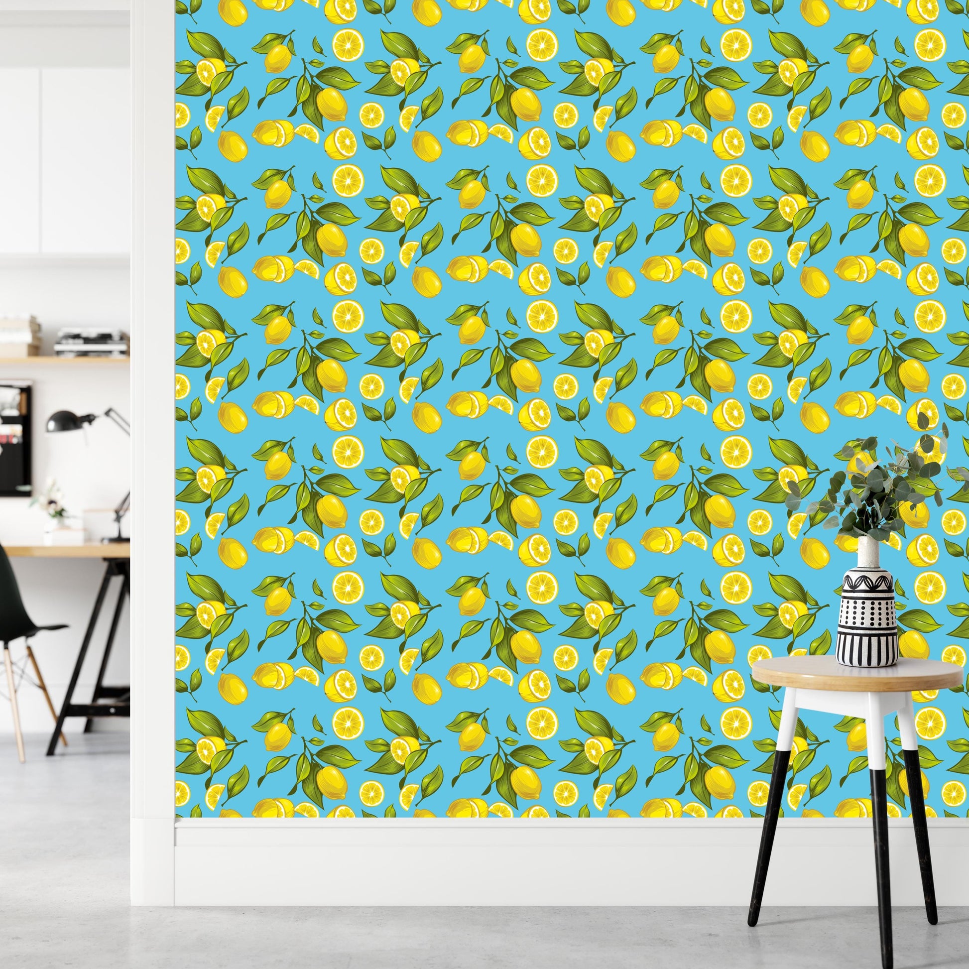 a wallpapered wall with a repeating pattern of yellow lemons and green leaves. In the foreground, there is a small table with a vase of flowers on it.