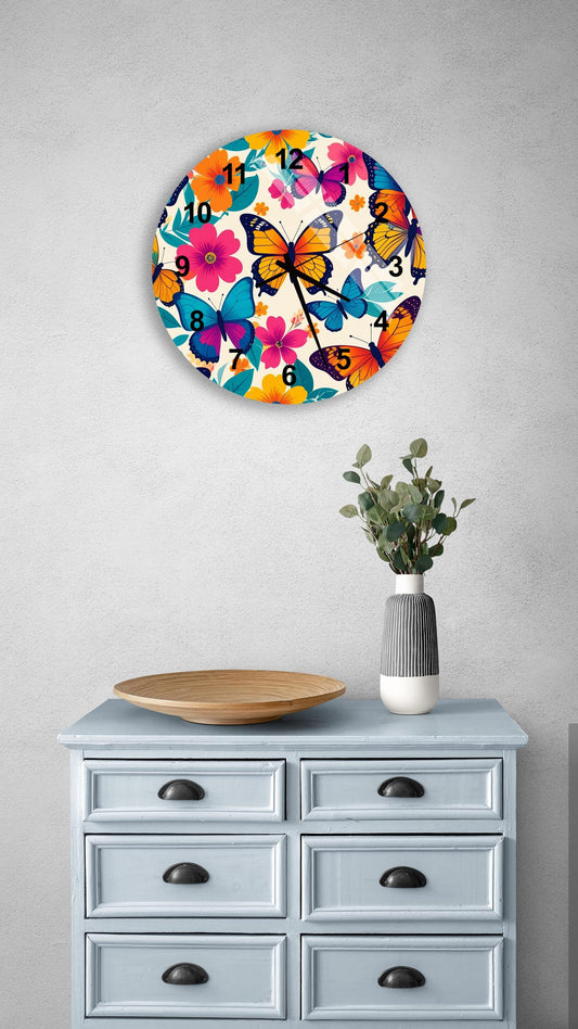 a round clock with a butterfly design on a wall above a light blue dresser with six drawers. The dresser also has a vase with greenery and a wooden bowl on top.