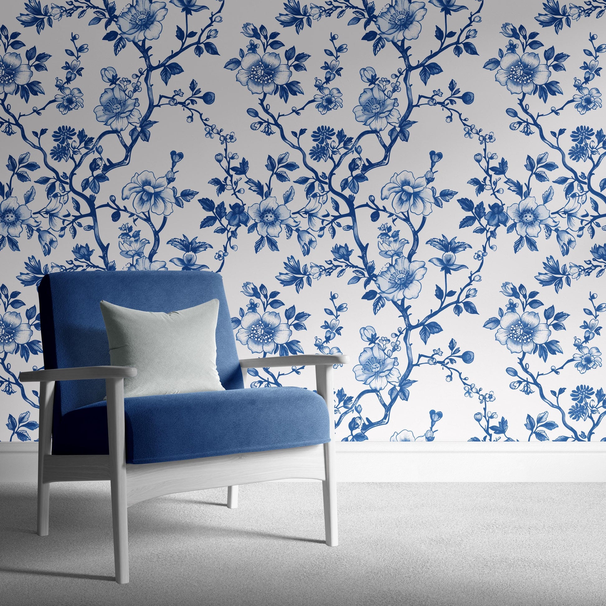 a blue armchair with a white pillow, set against a wall with a blue floral wallpaper.