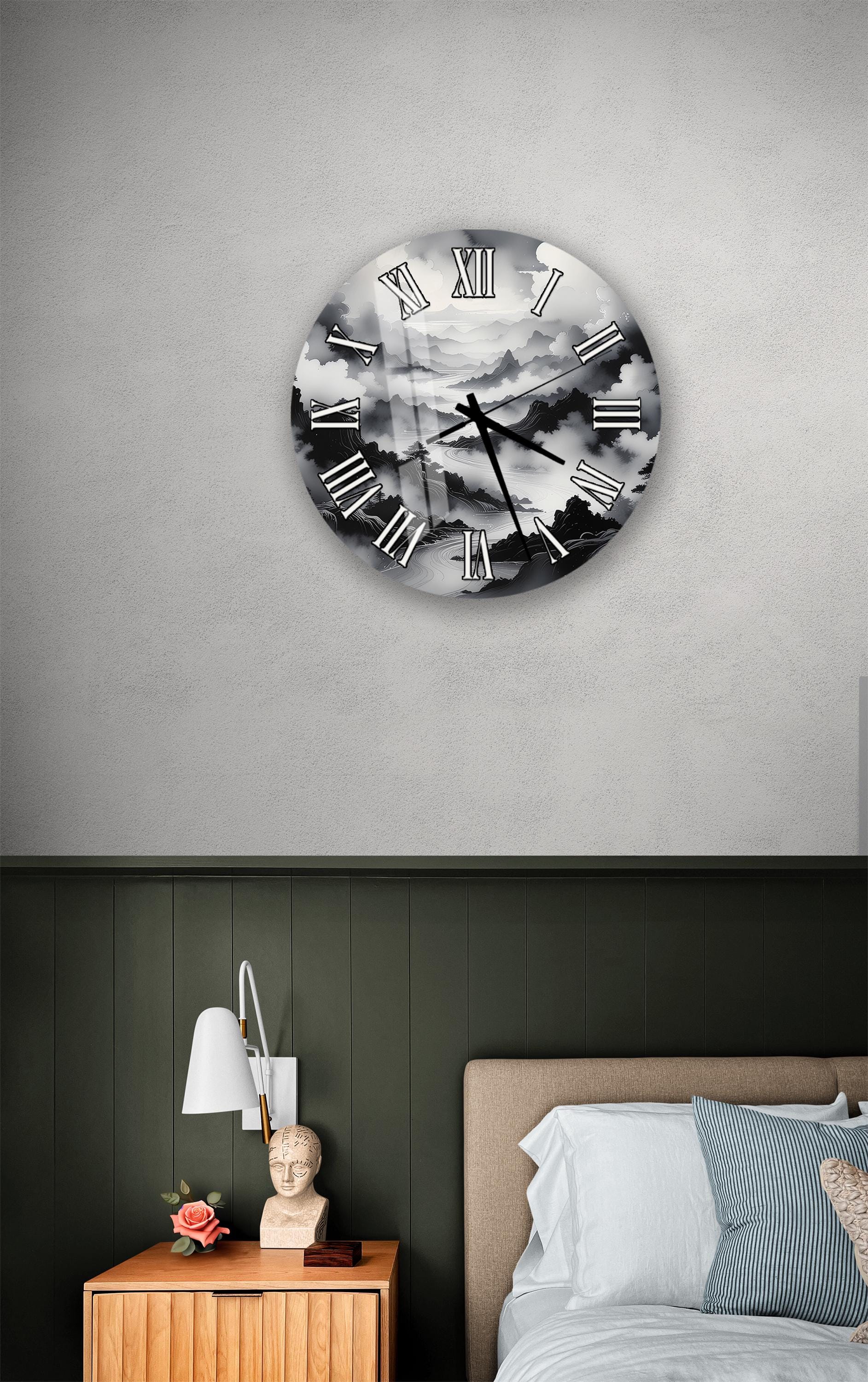 a bedroom setting with a large clock on the wall above a bed. The clock has a black and white design with clouds and mountains as its background. The room has a green wall, a wooden nightstand with a lamp, and a bed with white sheets.