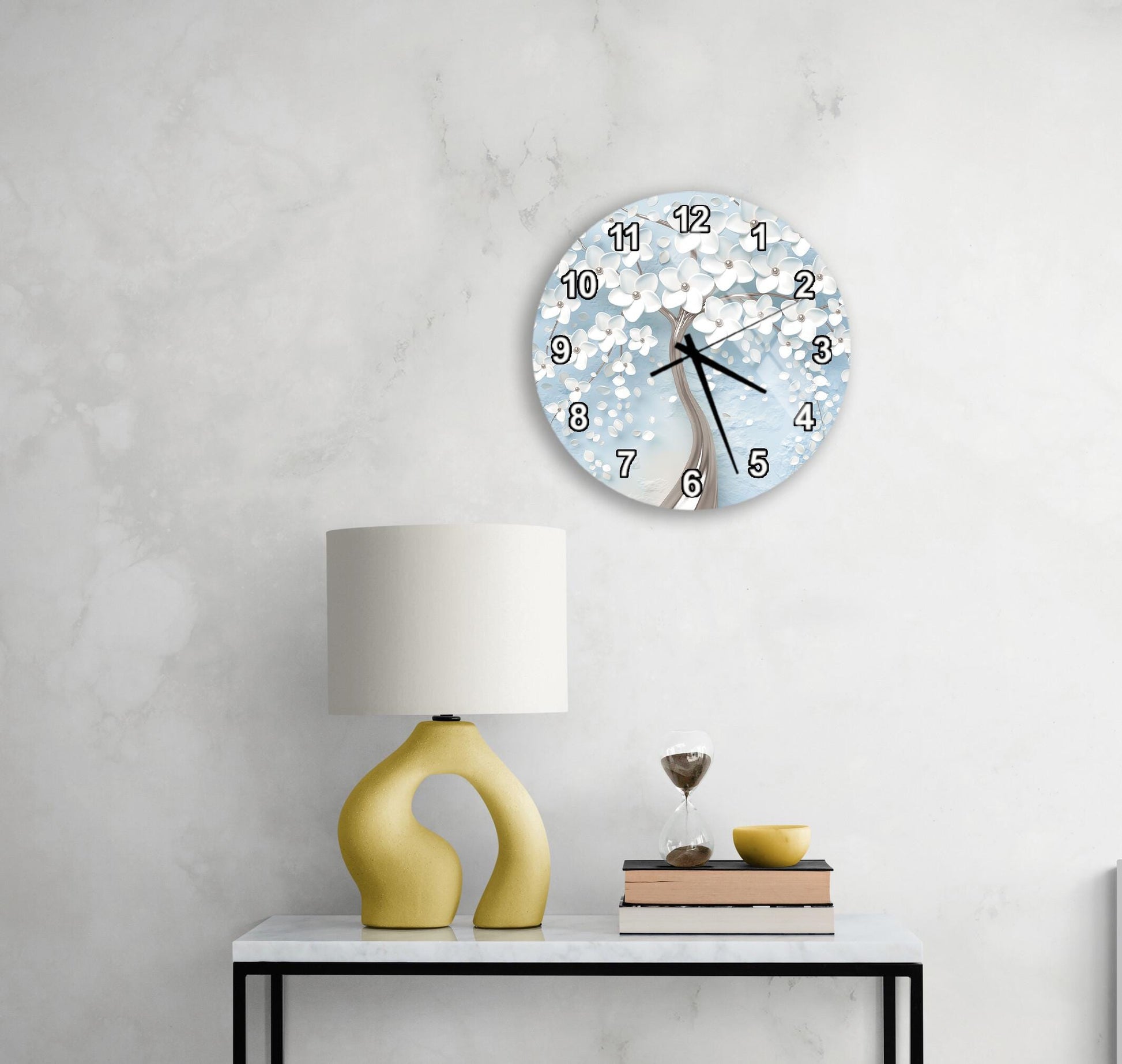 a modern living room with a white marble wall, a round clock with a blue and white floral design, a yellow lamp with a unique curved base, and a small table with a book and a glass of water.
