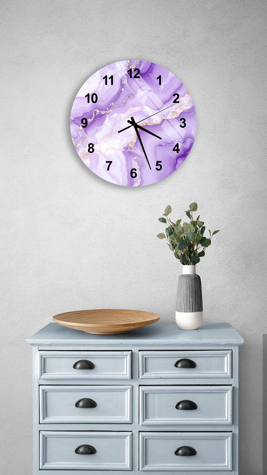 a purple marble wall clock with gold accents, mounted on a wall above a light blue wooden dresser with six drawers. The dresser also has a vase with greenery on it, and there is a wooden bowl on the dresser.