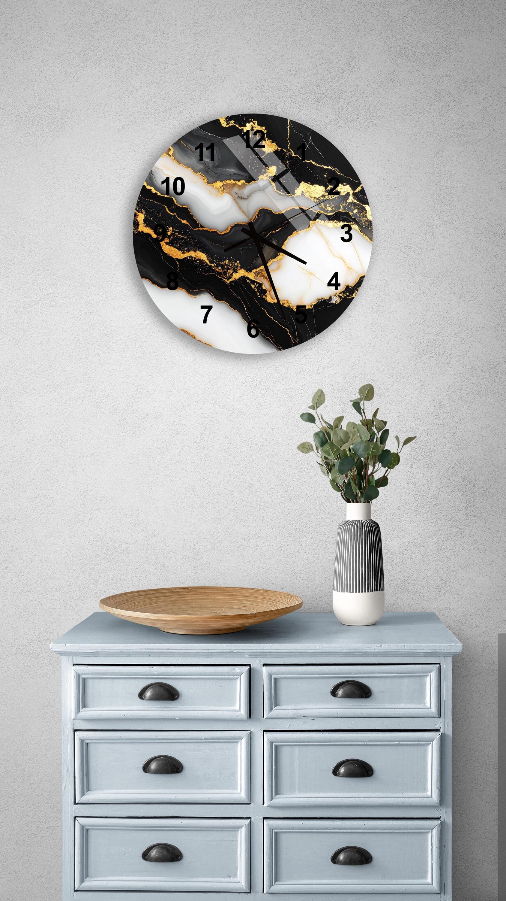 a wall clock with a black and white marble design, mounted on a wall above a light blue dresser with six drawers. The dresser also has a vase with greenery and a wooden tray on top.