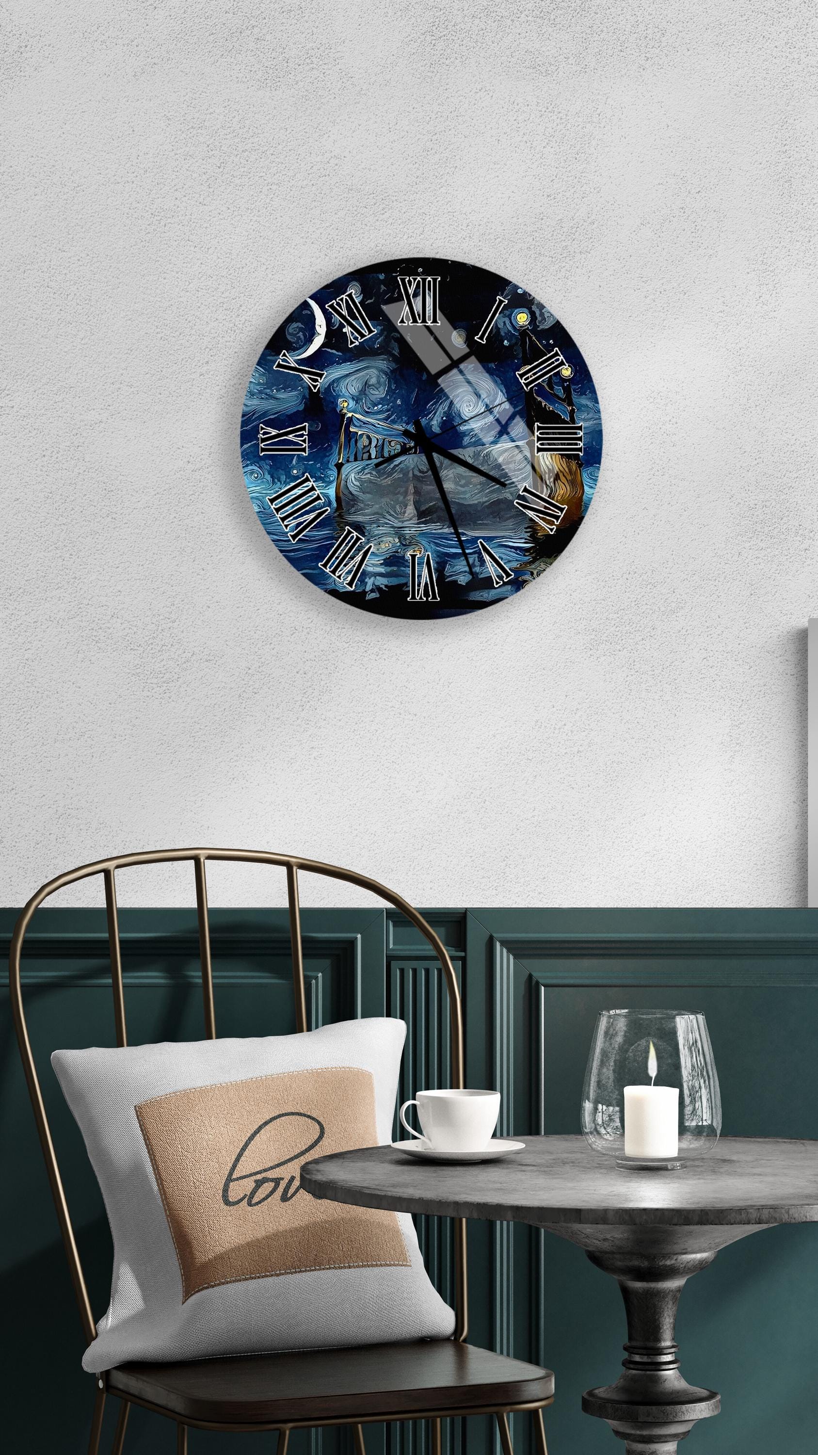 a round wall clock with a night sky and ocean design, mounted on a wall above a table with a white tablecloth and a candle.