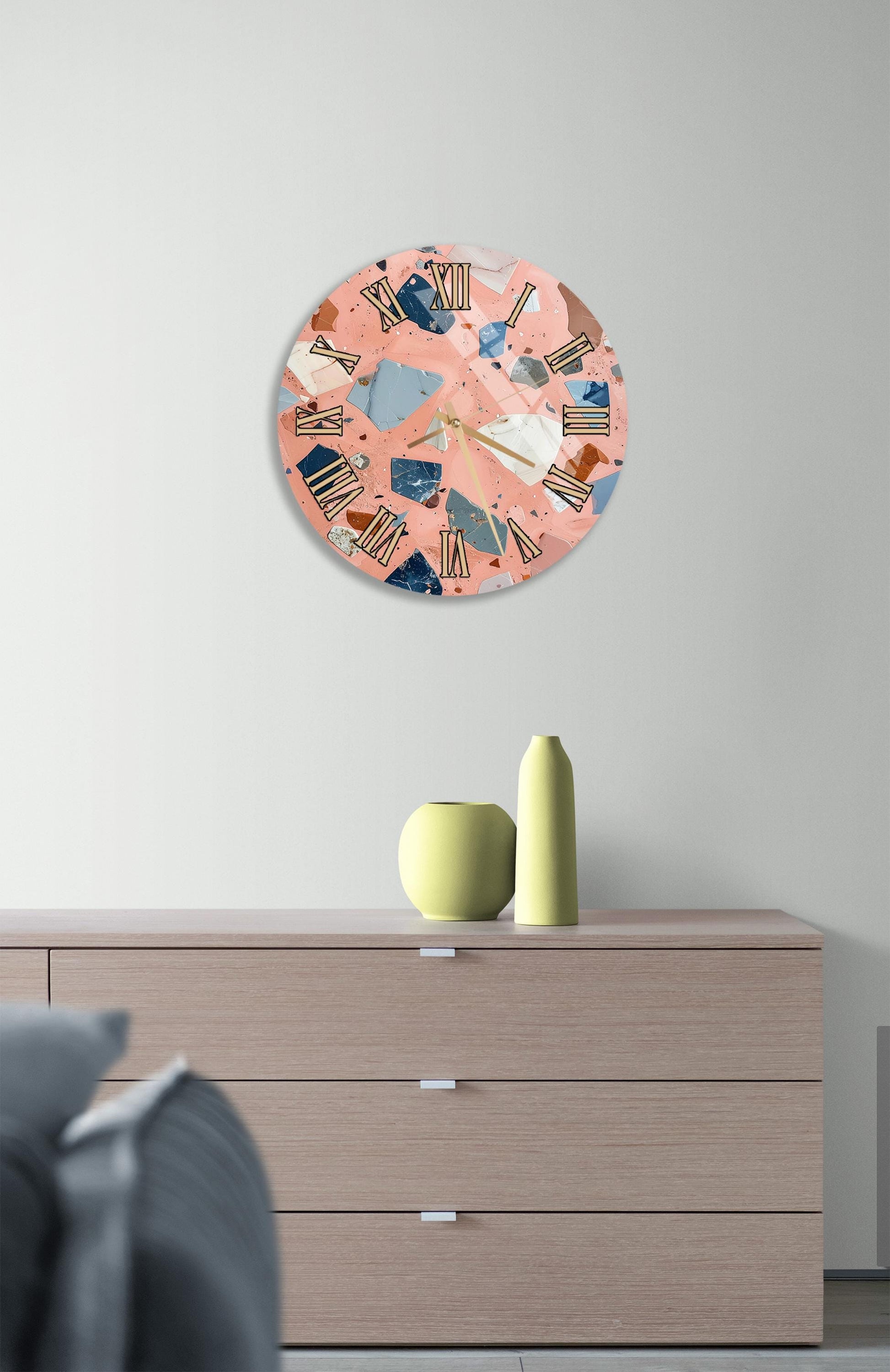a modern living room with a wooden dresser, a round clock with a colorful abstract design, and a small green vase on the dresser.