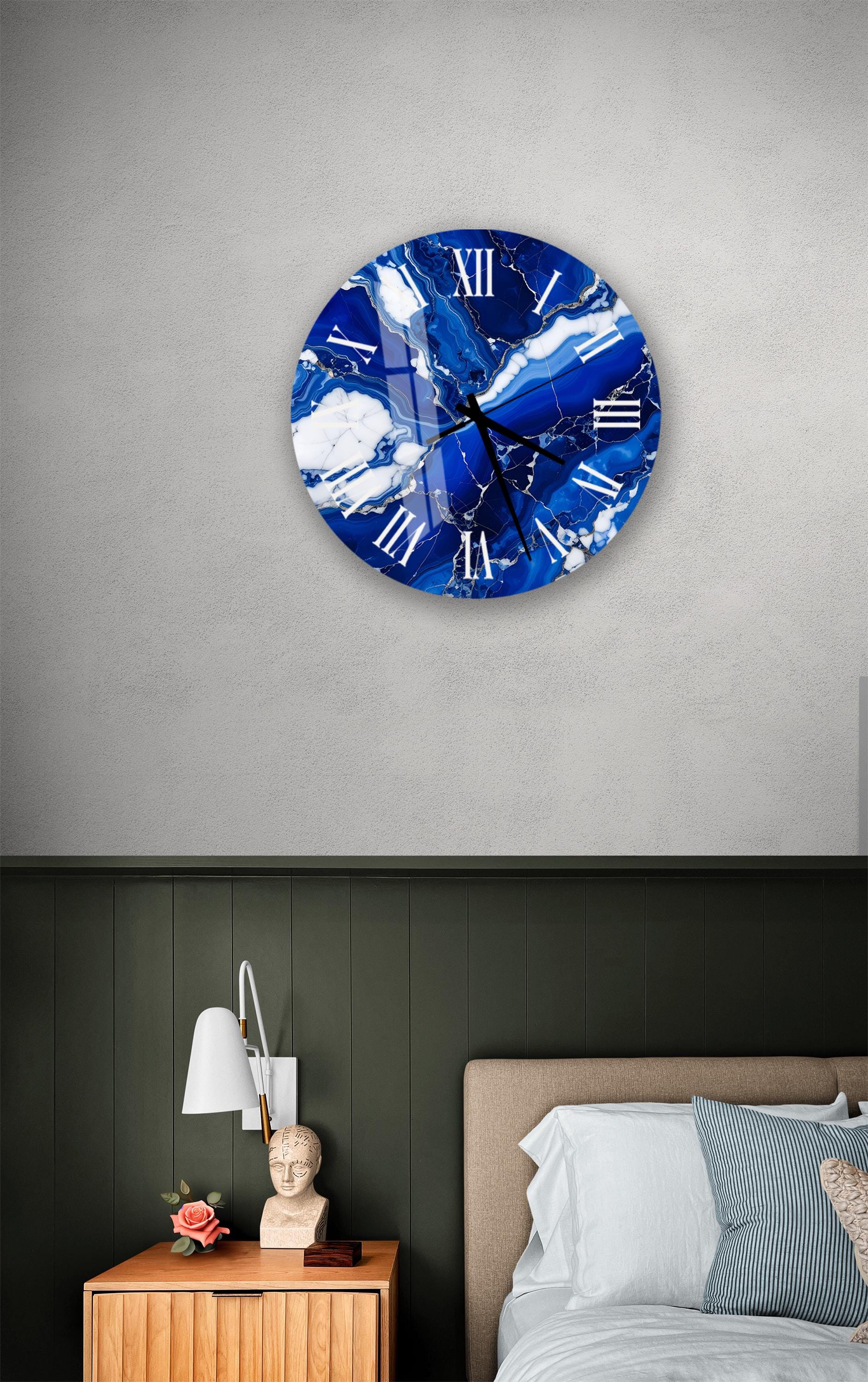a bedroom setting with a large blue and white marble clock hanging on the wall above a bed. The clock has Roman numerals and appears to be a wall clock.