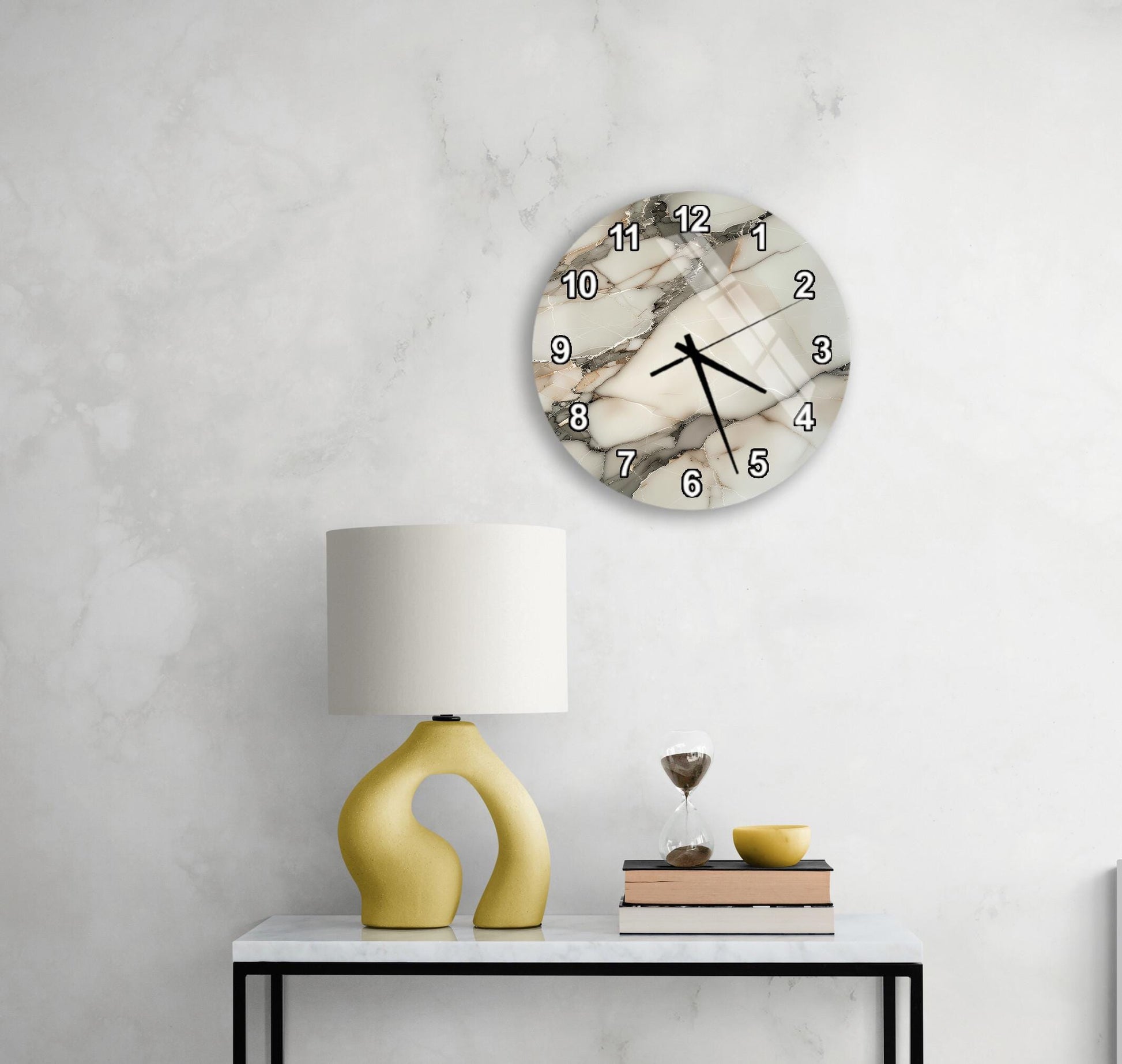 a modern living room with a white marble clock mounted on the wall above a white table with a yellow lamp and a stack of books.