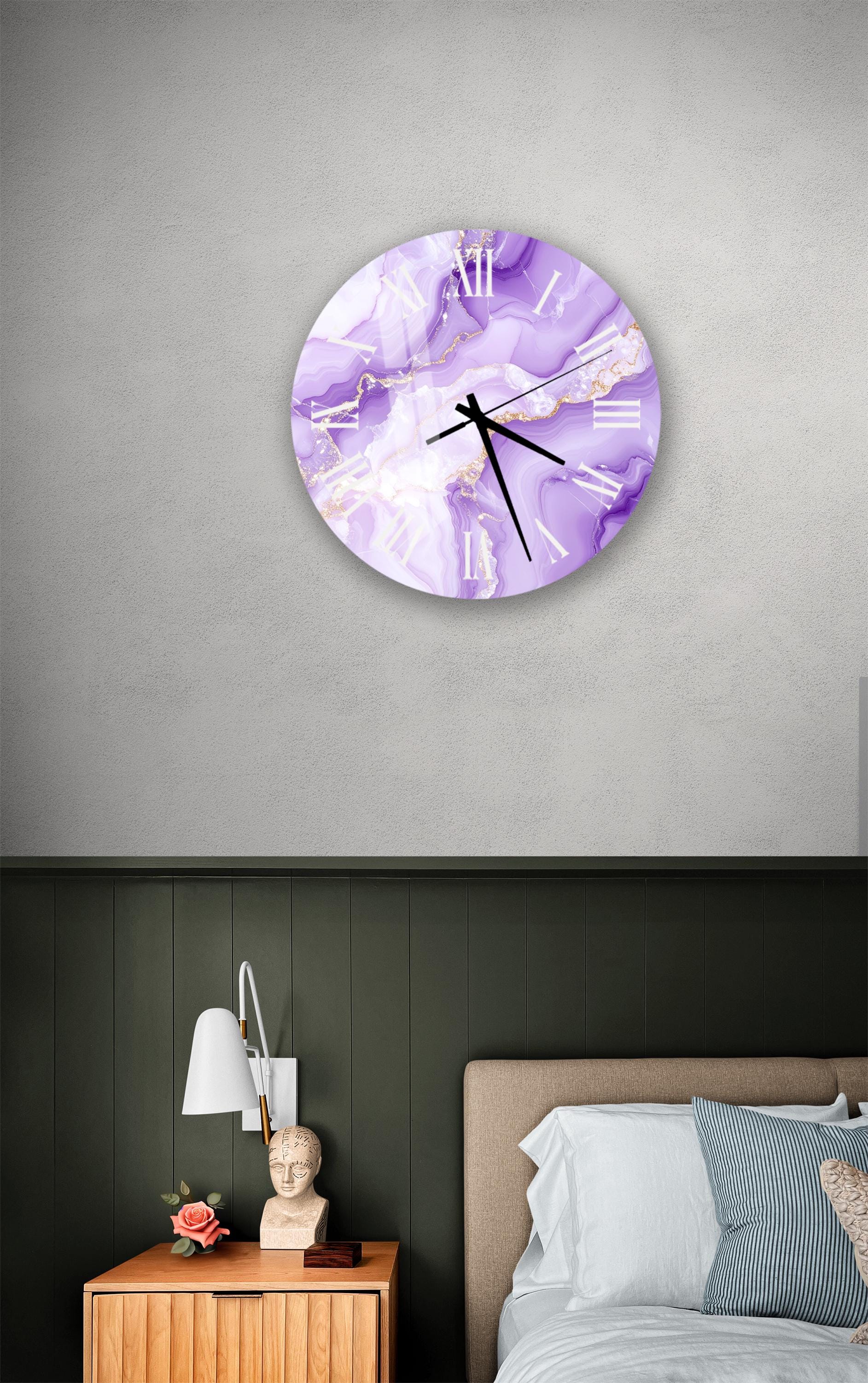 a bedroom setting with a large purple marble-style clock hanging on the wall above a bed. The clock has a white face with black Roman numerals and appears to be a decorative piece. The room also includes a nightstand with a lamp and a small statue or bust.