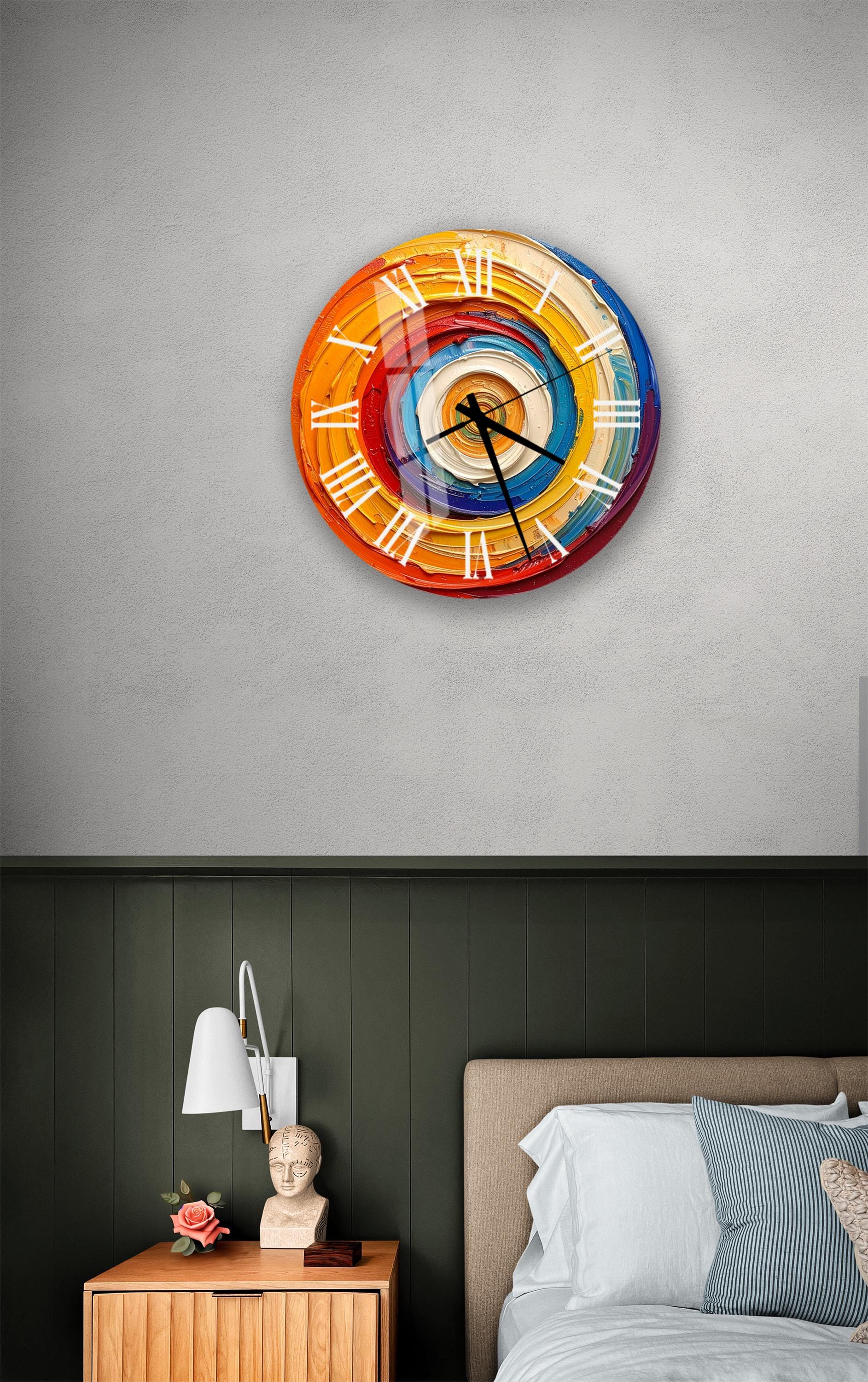 a colorful, abstract wall clock with a spiral design, mounted on a wall above a bedside table with a lamp and a small statue.