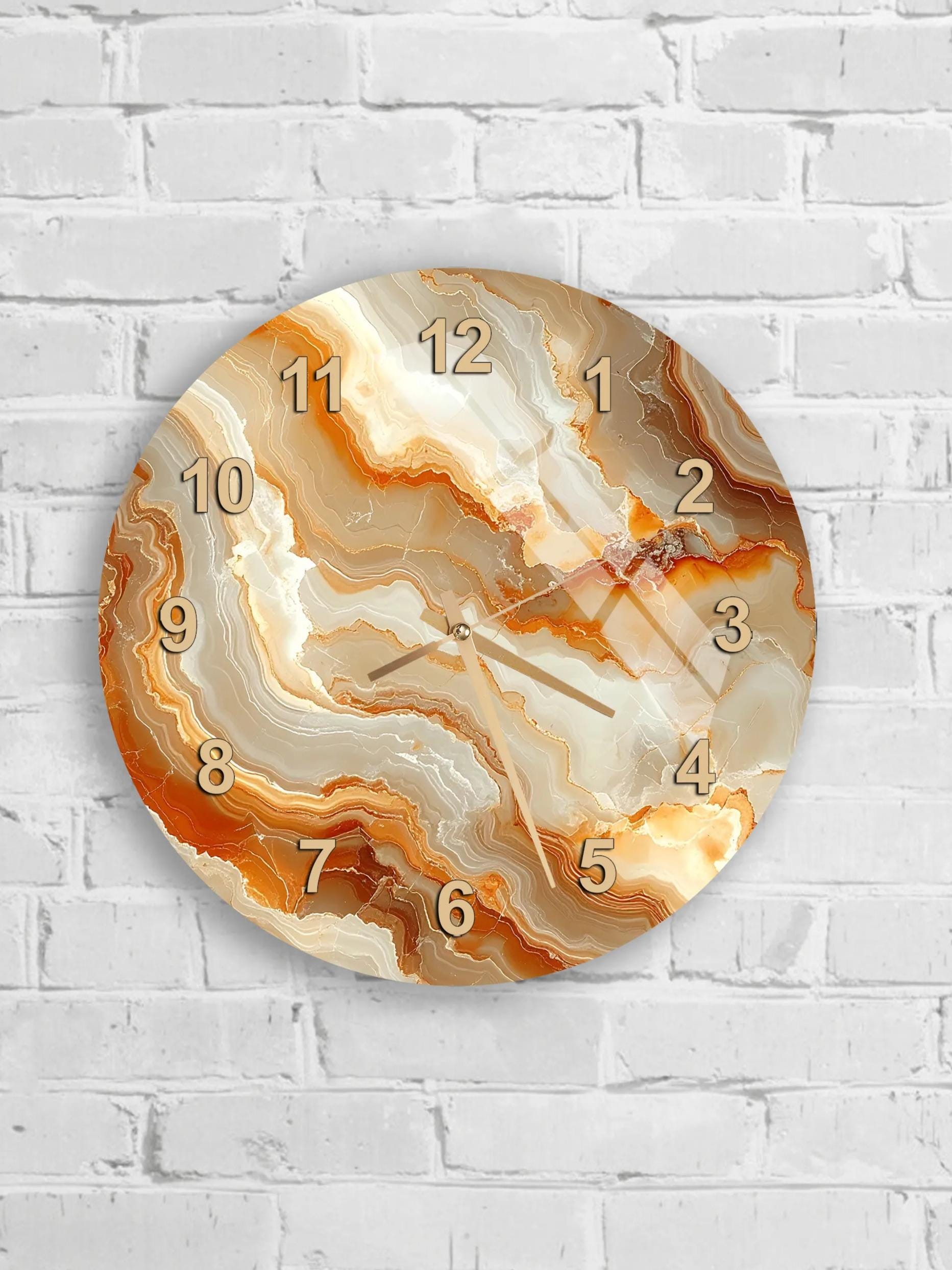 A round wall clock with a marble-like design in shades of orange and beige, mounted on a white brick wall.