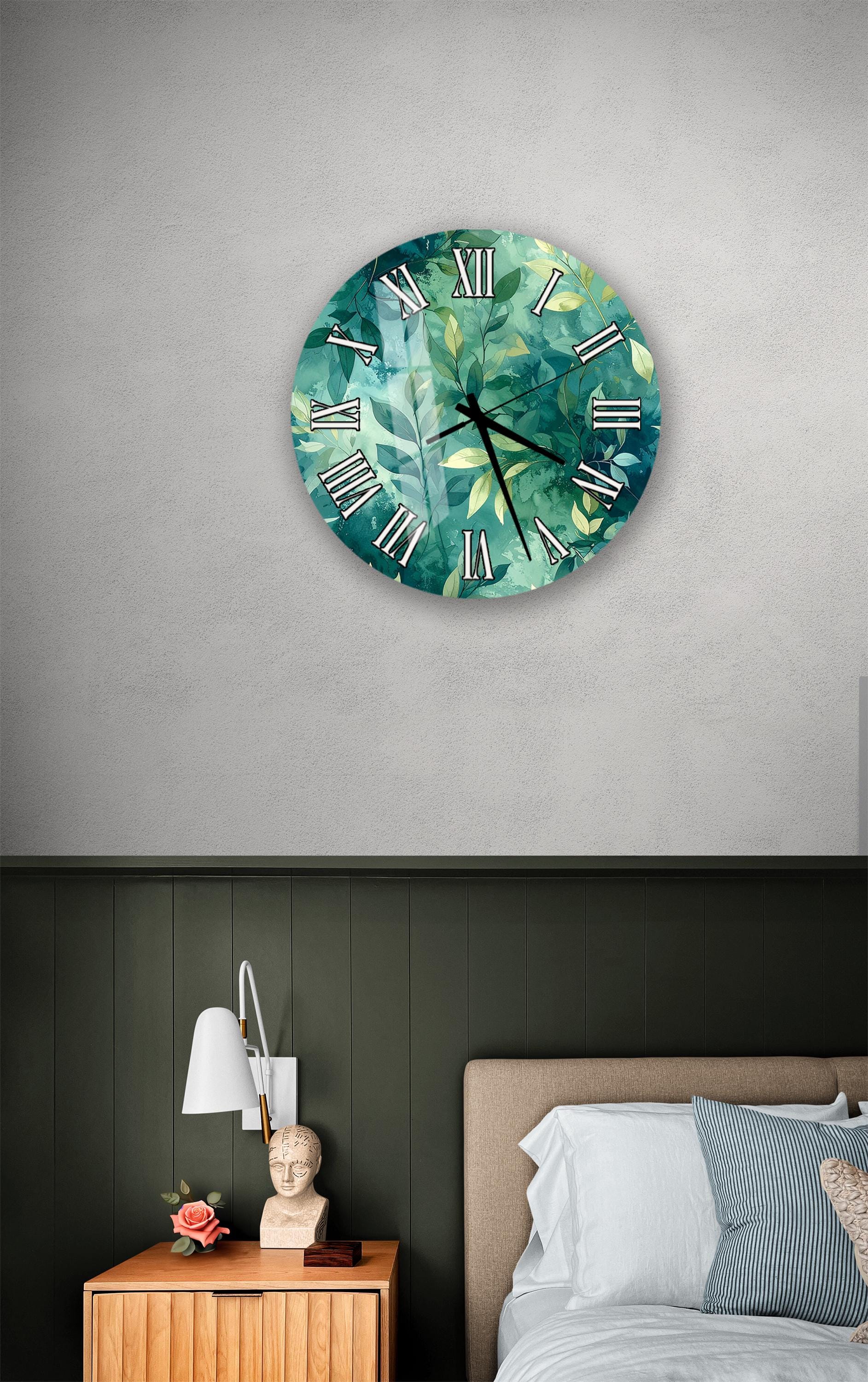 a bedroom setting with a large wall clock displaying a green leafy pattern, a wooden nightstand with a lamp, and a bed with white pillows.