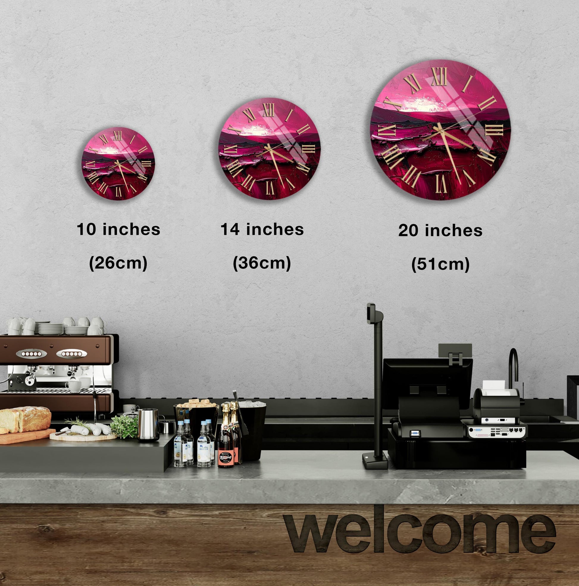 a wall clock with a pink and purple design, and there are three different sizes of the clock displayed on the wall. In the foreground, there is a counter with various items such as bottles and a sandwich. The word "welcome" is written on the counter.