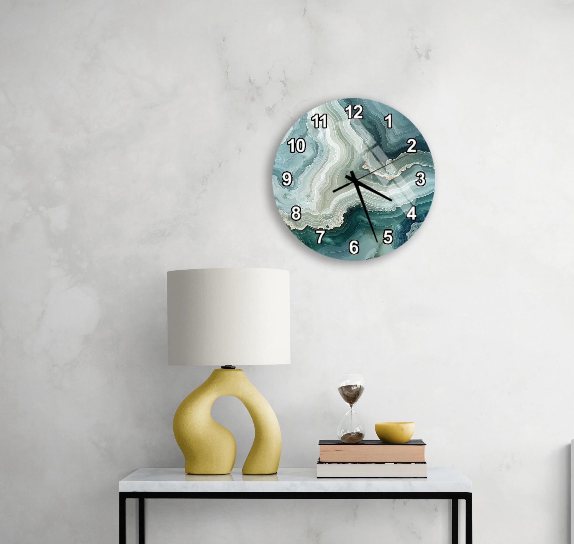 a modern living room with a white marble wall, a round clock with a marble design, a yellow lamp with a unique curved base, and a small table with a book and a glass of wine.