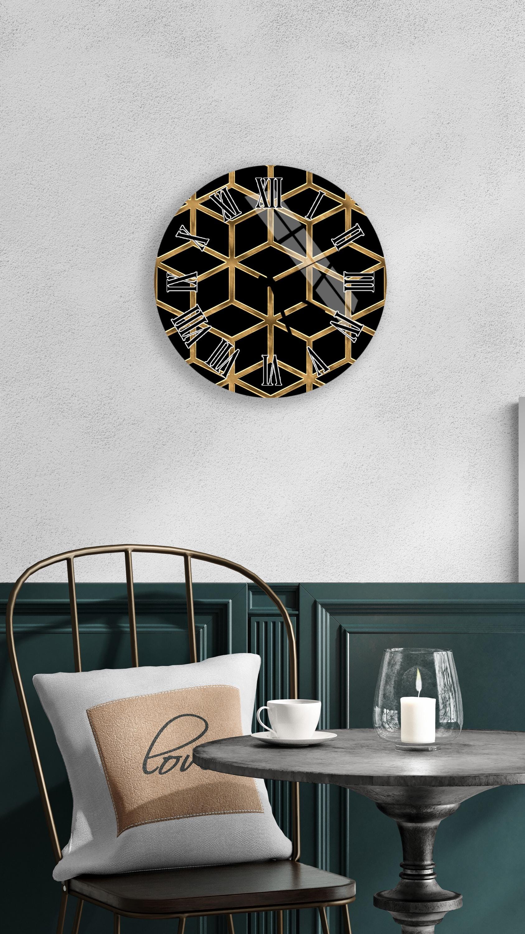 a modern and stylish interior design with a black and gold hexagonal clock mounted on a white wall above a black metal chair. The chair is positioned in front of a small round table with a white tablecloth, and a candle is lit on the table.