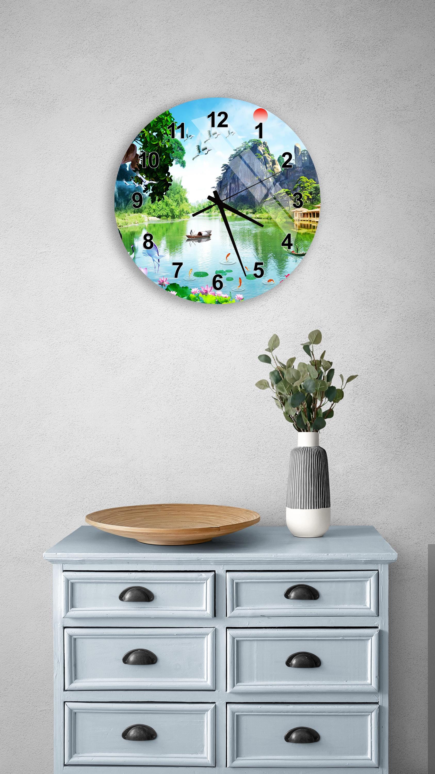 a wall clock with a scenic landscape design, mounted on a wall above a light blue dresser with drawers.
