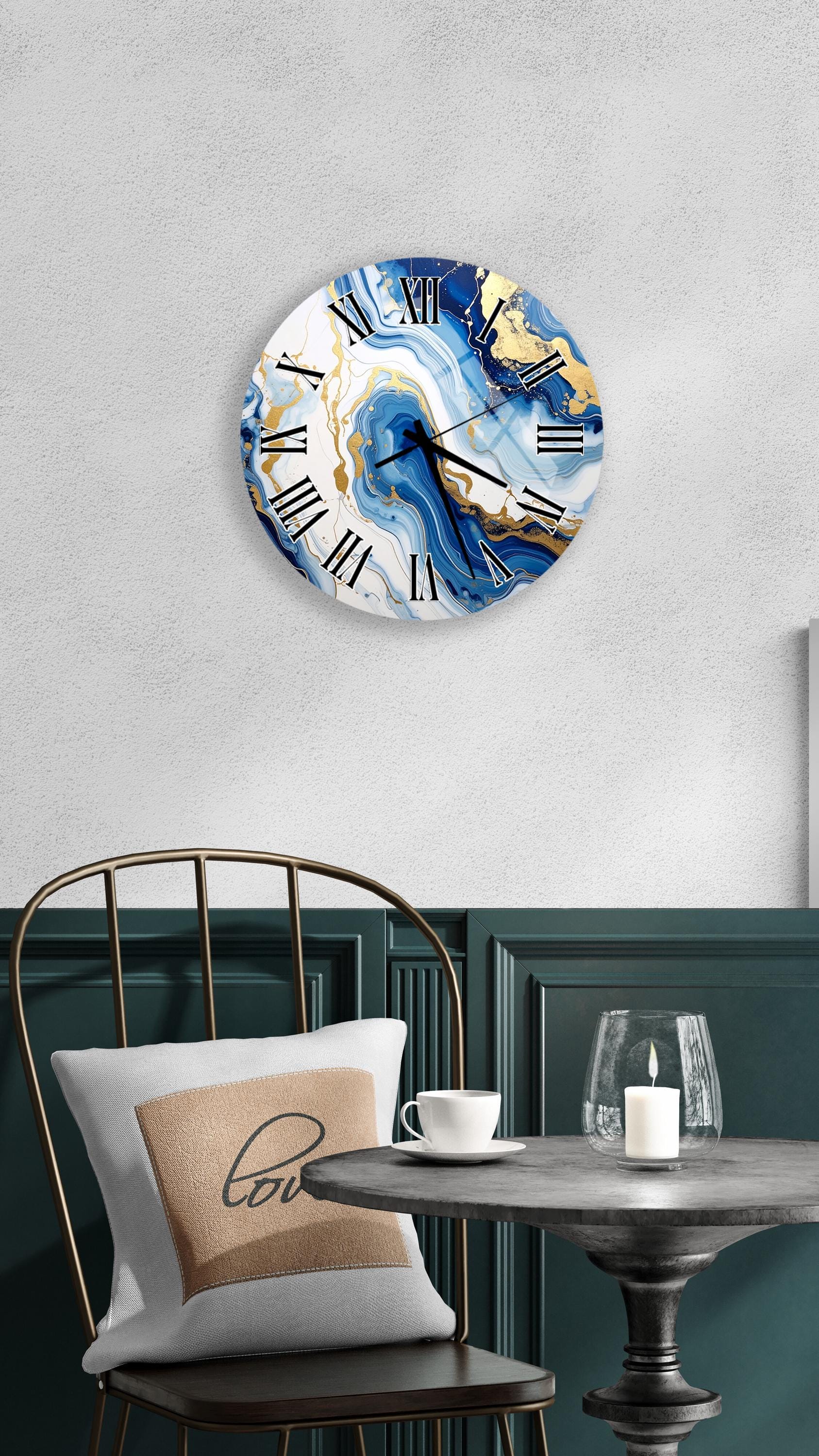 a modern interior design with a round wall clock with a marble-like blue and white swirl pattern, a white table with a candle and a glass, and a black metal chair with a white pillow.