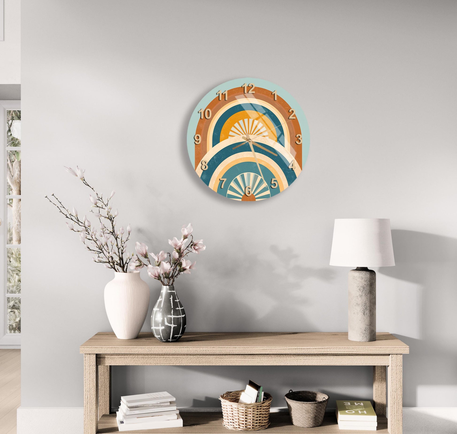 a modern and minimalist living room with a wooden console table, a round wall clock with a colorful design, and various decorative items such as a vase with flowers, a lamp, and a stack of books.