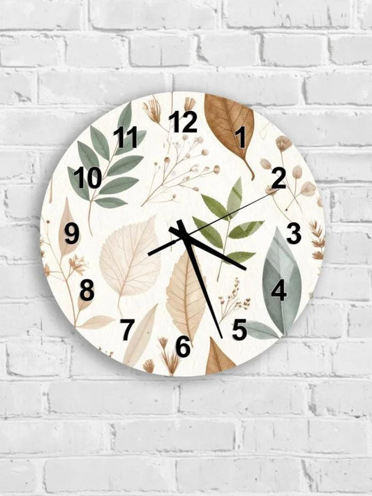 A round wall clock with a leaf and flower design on its face, mounted on a white brick wall.