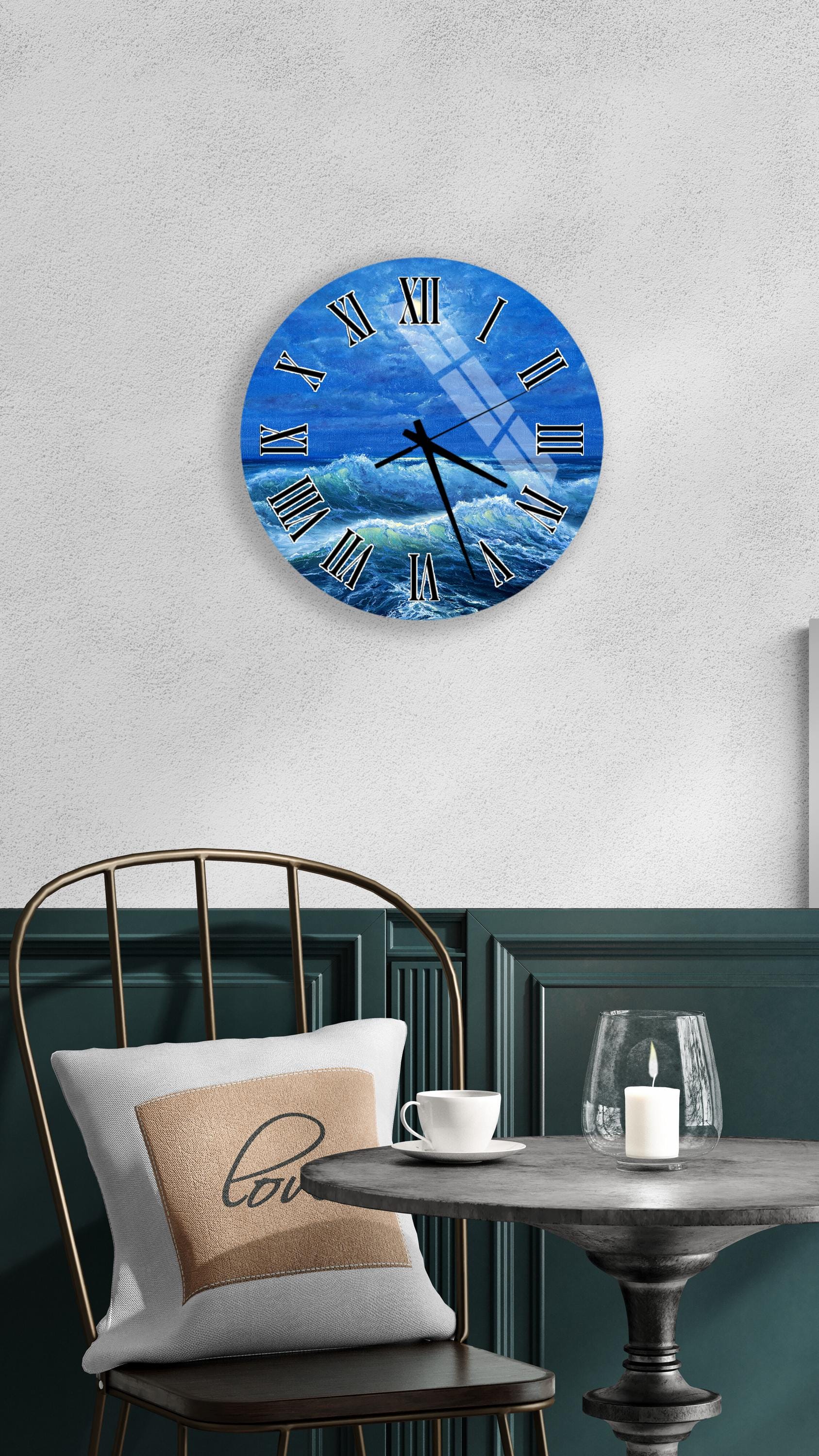 a wall clock with a blue ocean scene, a white table with a candle and a cup, and a chair with a pillow.