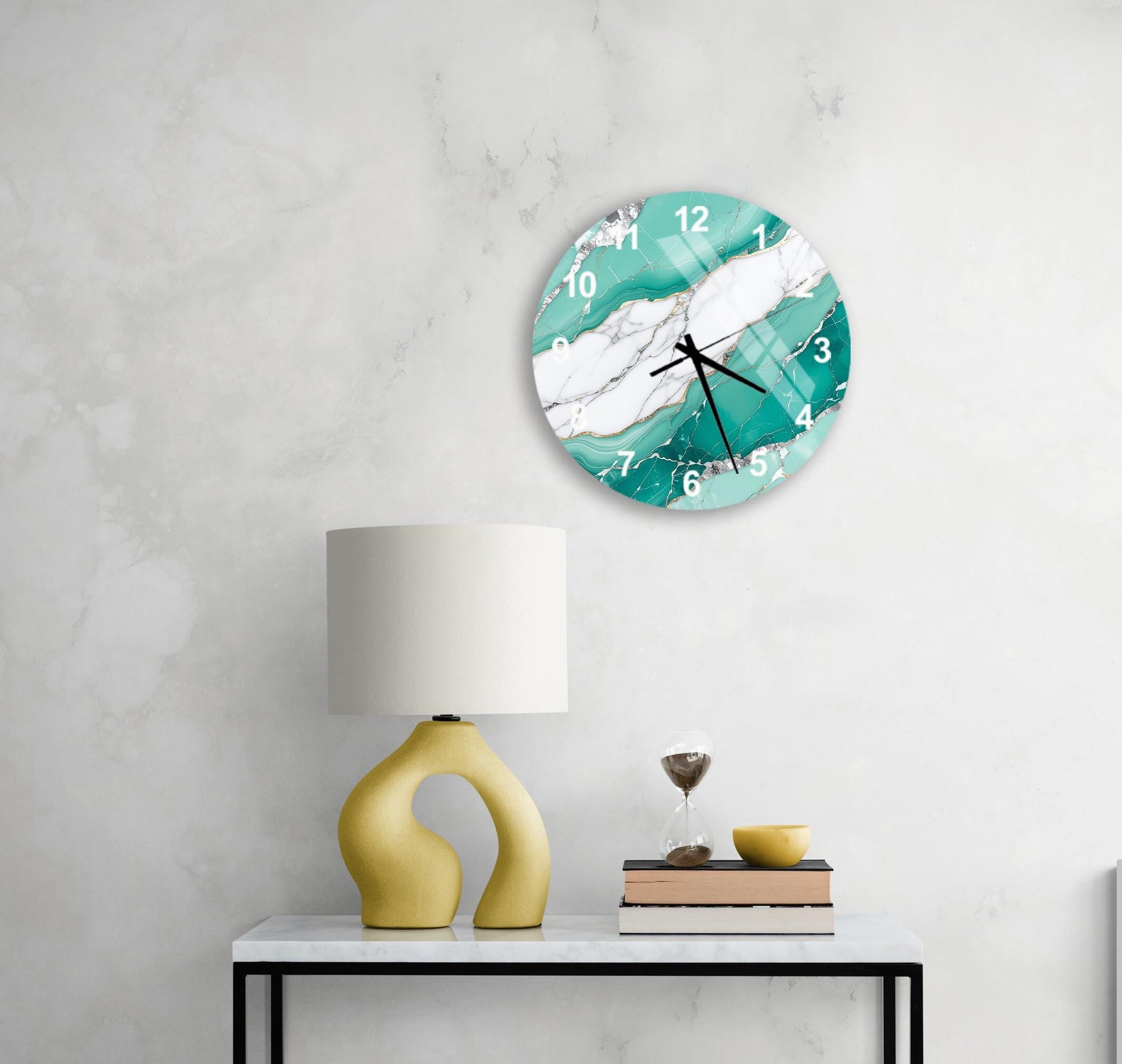 a white marble clock with turquoise and white marble design, mounted on a wall above a white table with a yellow lamp and a stack of books.