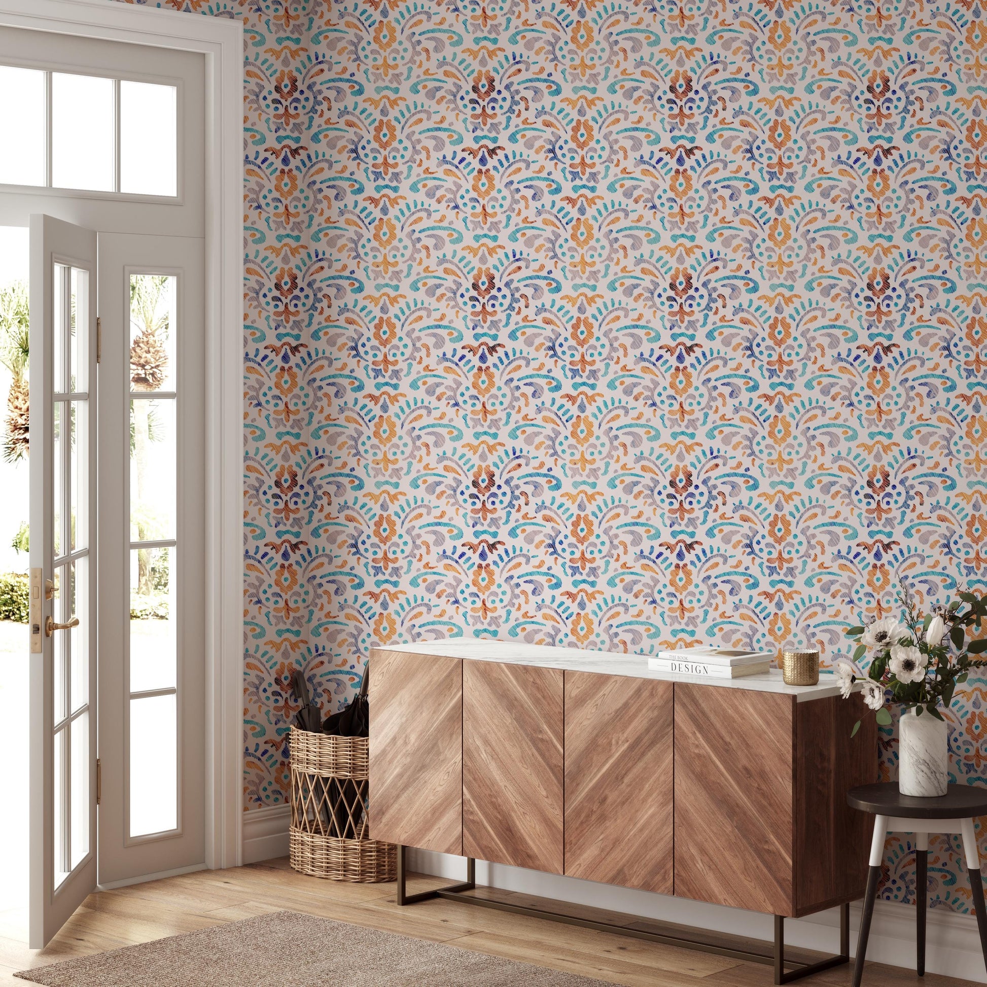 a room with a vibrant, patterned wallpaper, a wooden cabinet, a wicker basket, and a small table with a vase of flowers.