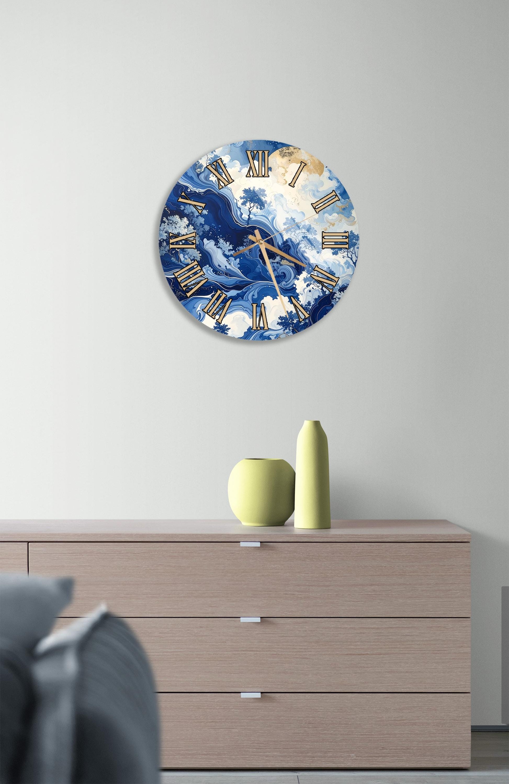 a wall clock with a blue and white marble design, mounted on a wall above a wooden dresser with a vase and a small sculpture on top.