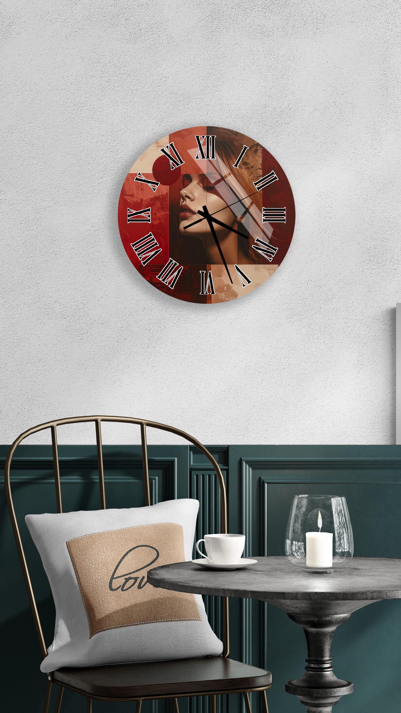 a wall clock with a red face and black Roman numerals, mounted on a white wall above a dining table with a white tablecloth. A white candle is lit on the table, and a white mug is placed on the table. A white pillow with the word "love" printed on it is also present on the chair.