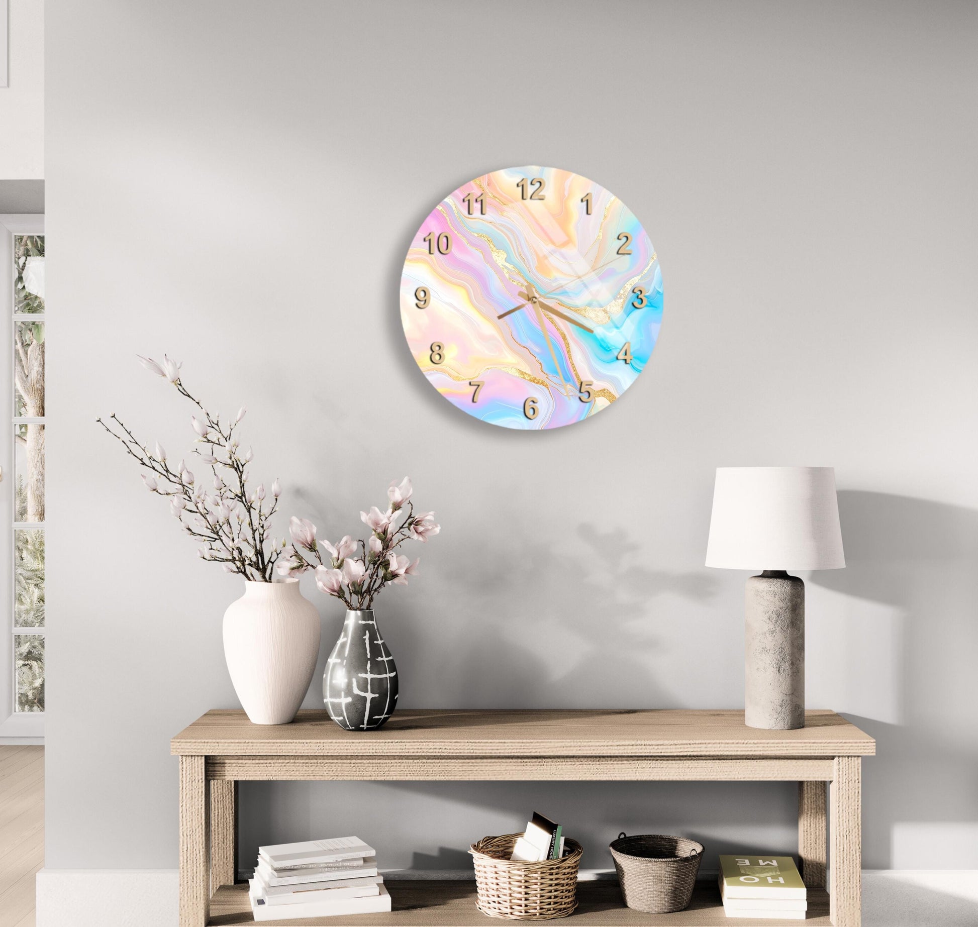 a wall clock with a marble-like design, a wooden table with a lamp, a vase with flowers, and some books on a shelf.