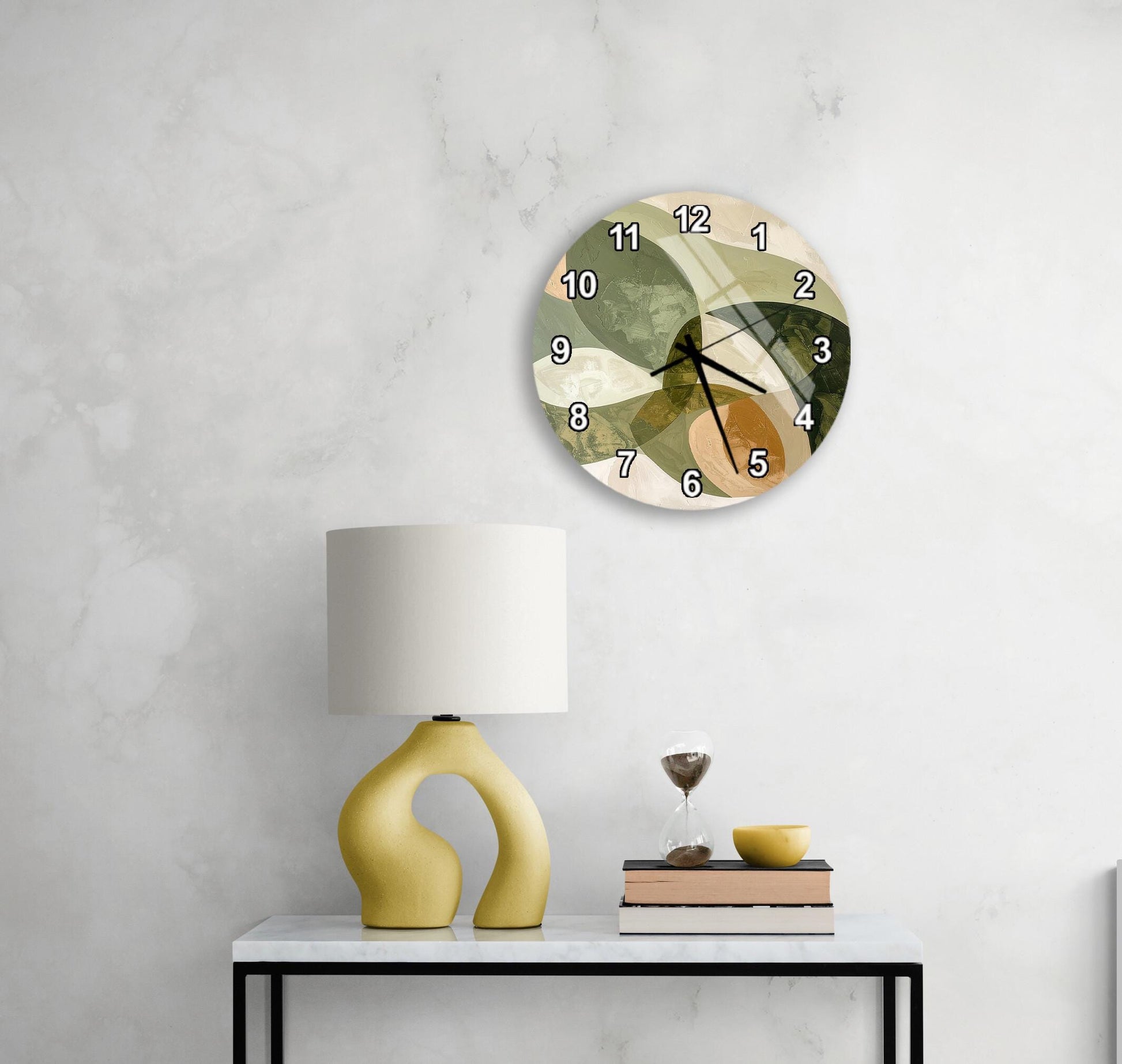 a modern, abstract-style clock with a unique design hanging on a wall above a white table with a yellow lamp and a stack of books.