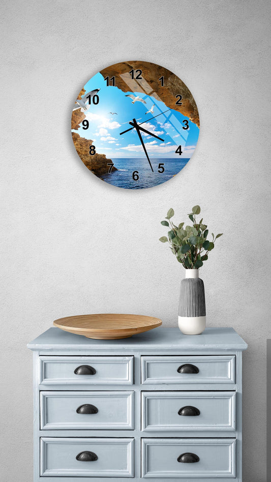 a wall clock with a beach scene on its face, mounted on a wall above a light blue dresser with drawers.